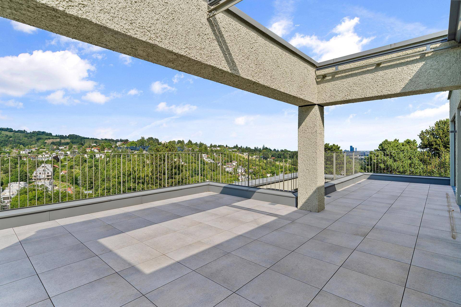 Weitläufige Terrasse mit Überdachung und Panoramablick auf die hügelige Landschaft und die Stadt.
