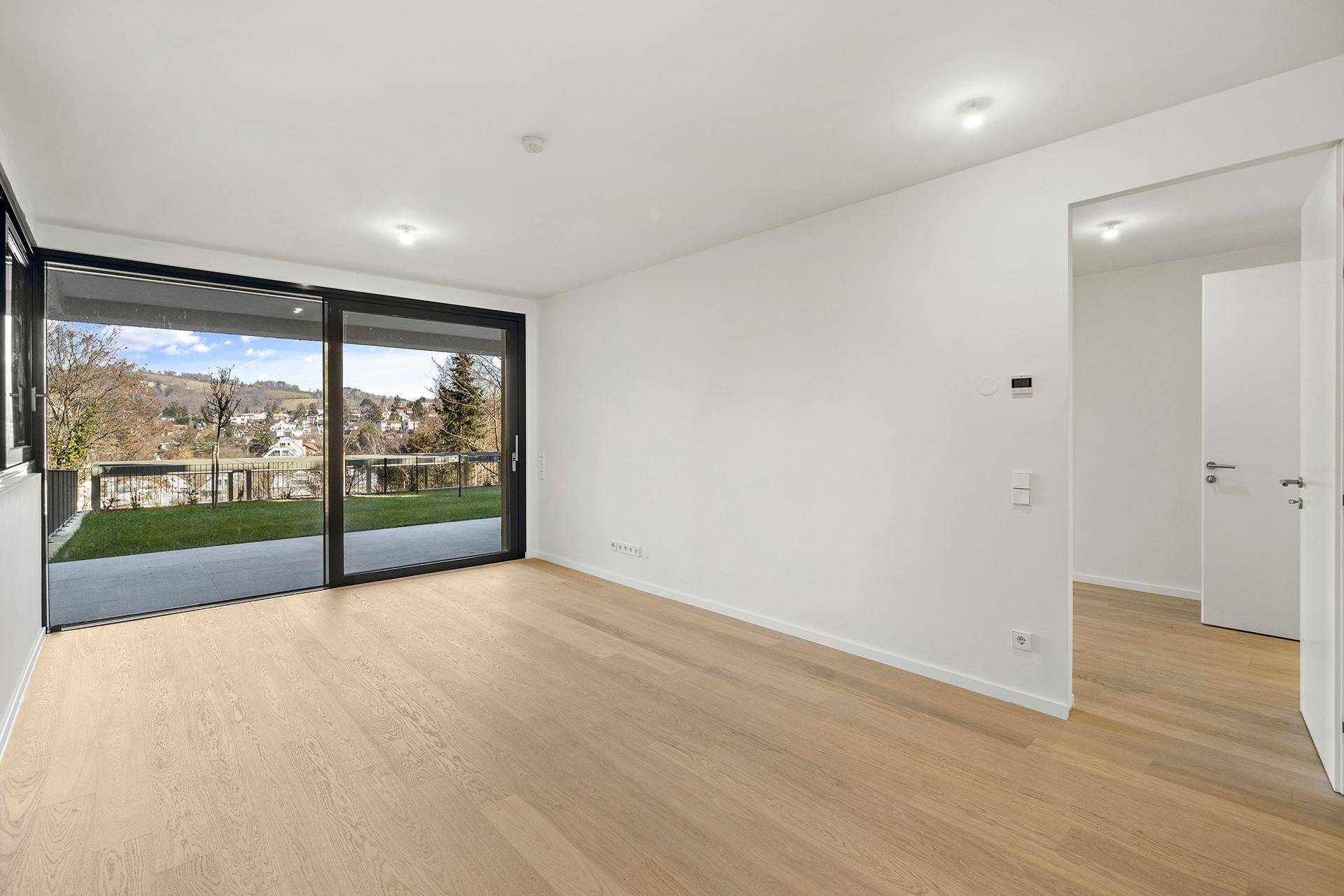 Helles Wohnzimmer mit Eichenparkett und großer Schiebetür zum Garten, bietet viel Tageslicht.