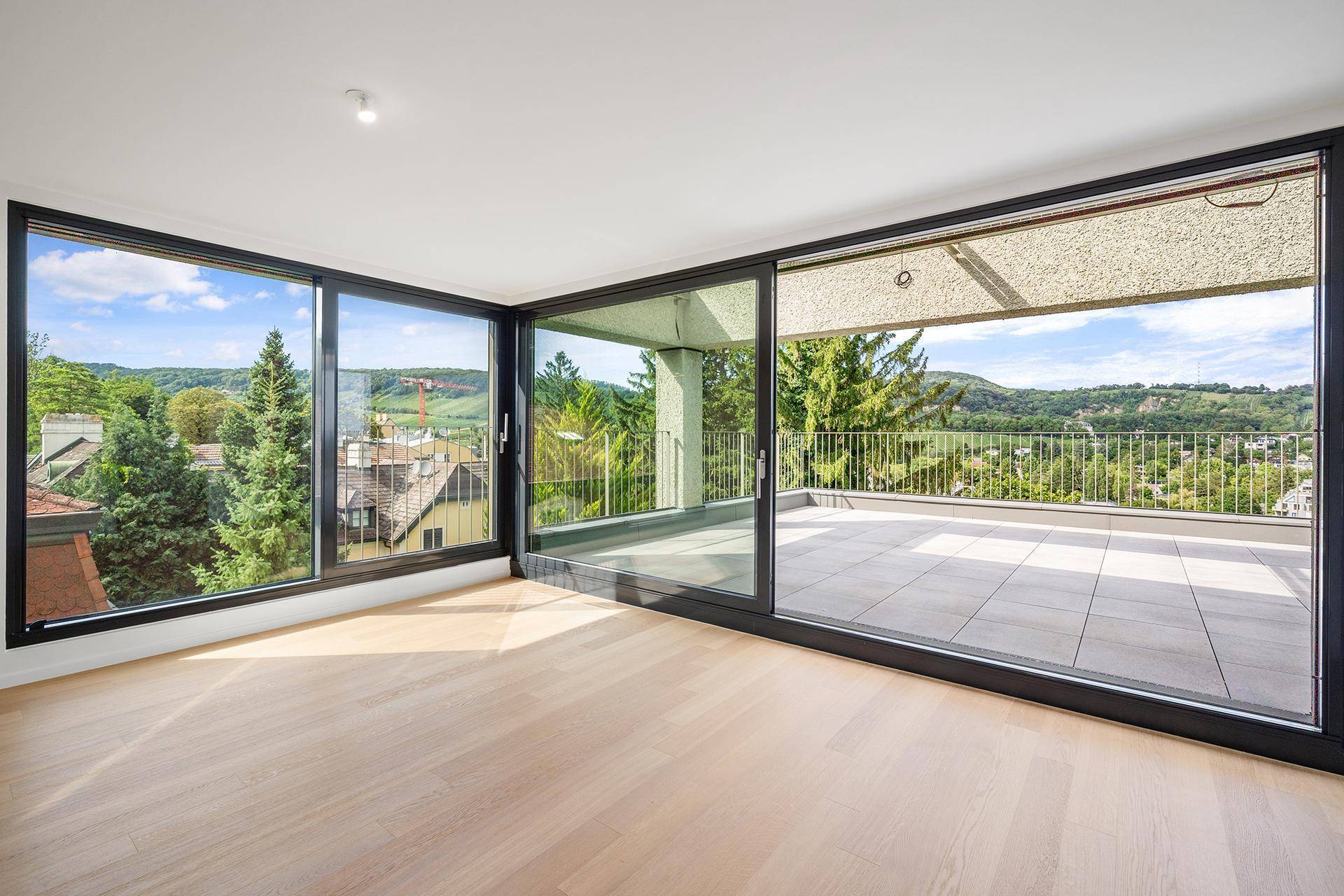 Heller Wohnraum mit großen Schiebetüren und Zugang zu einer weitläufigen Terrasse mit Panoramablick.