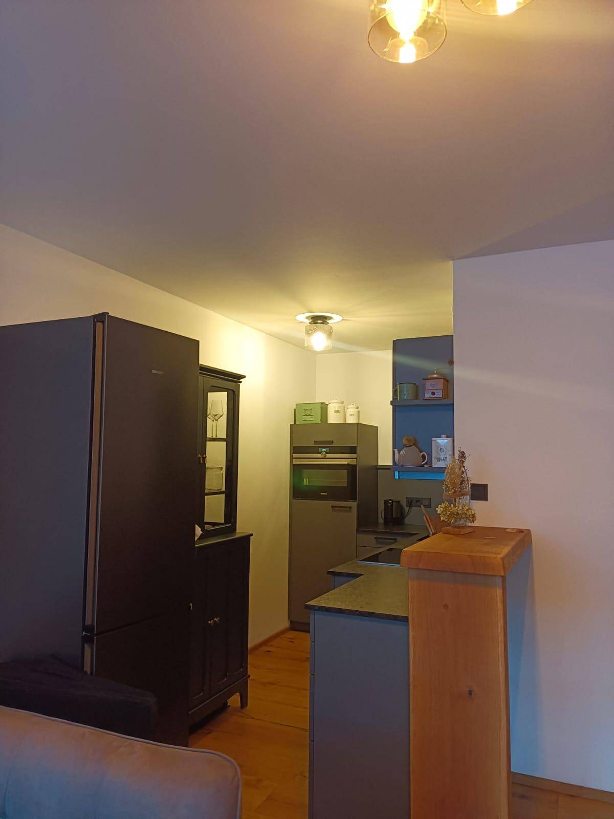 Moderne Küche mit dunklen Einbauschränken, integrierten Geräten und Holzboden.