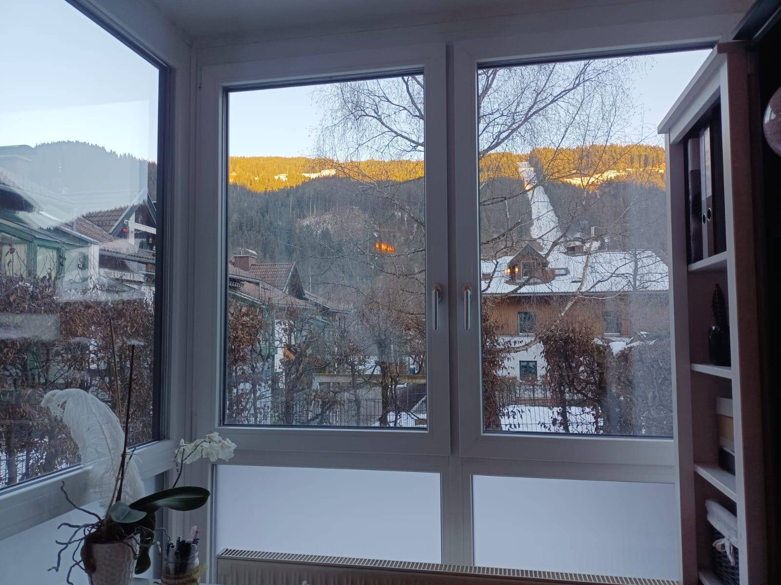 Große Fenster bieten einen weiten Blick auf schneebedeckte Berge und die umliegende Landschaft.