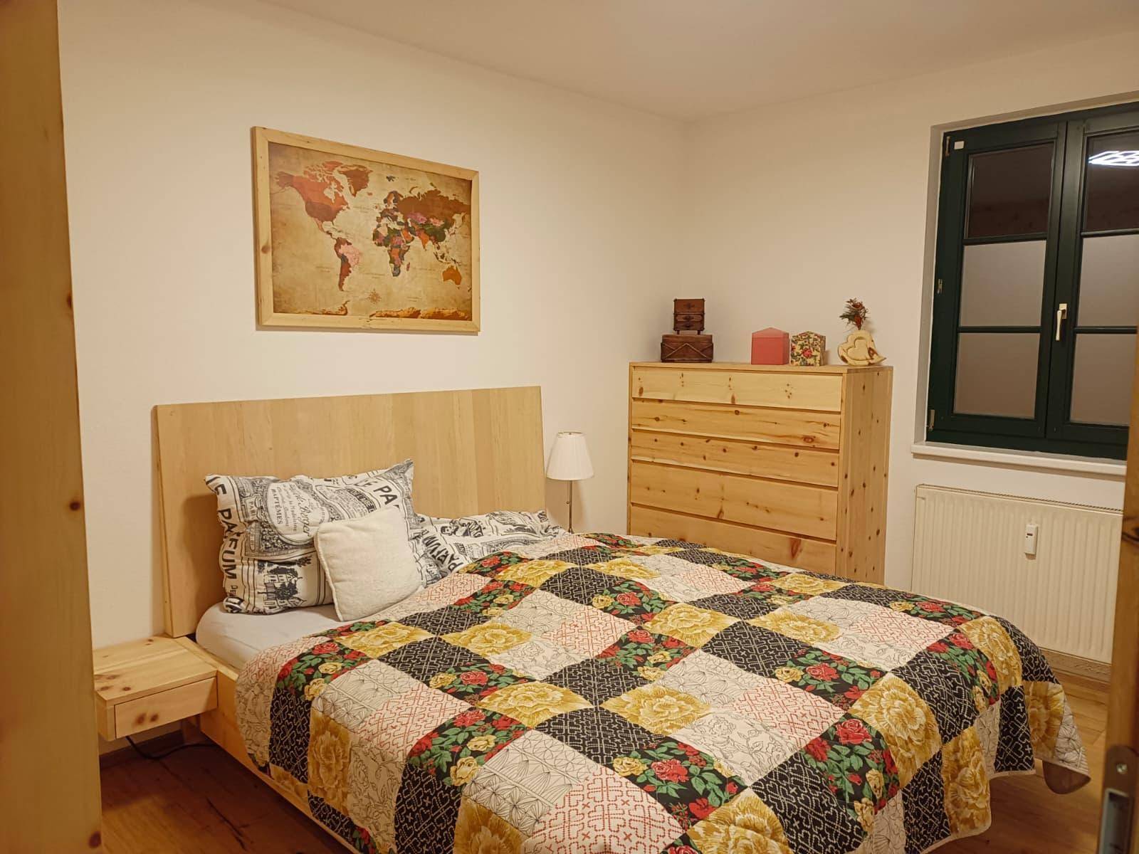 Helles Schlafzimmer mit Holzbett, Nachttischen und einem bunten Patchwork-Quilt.