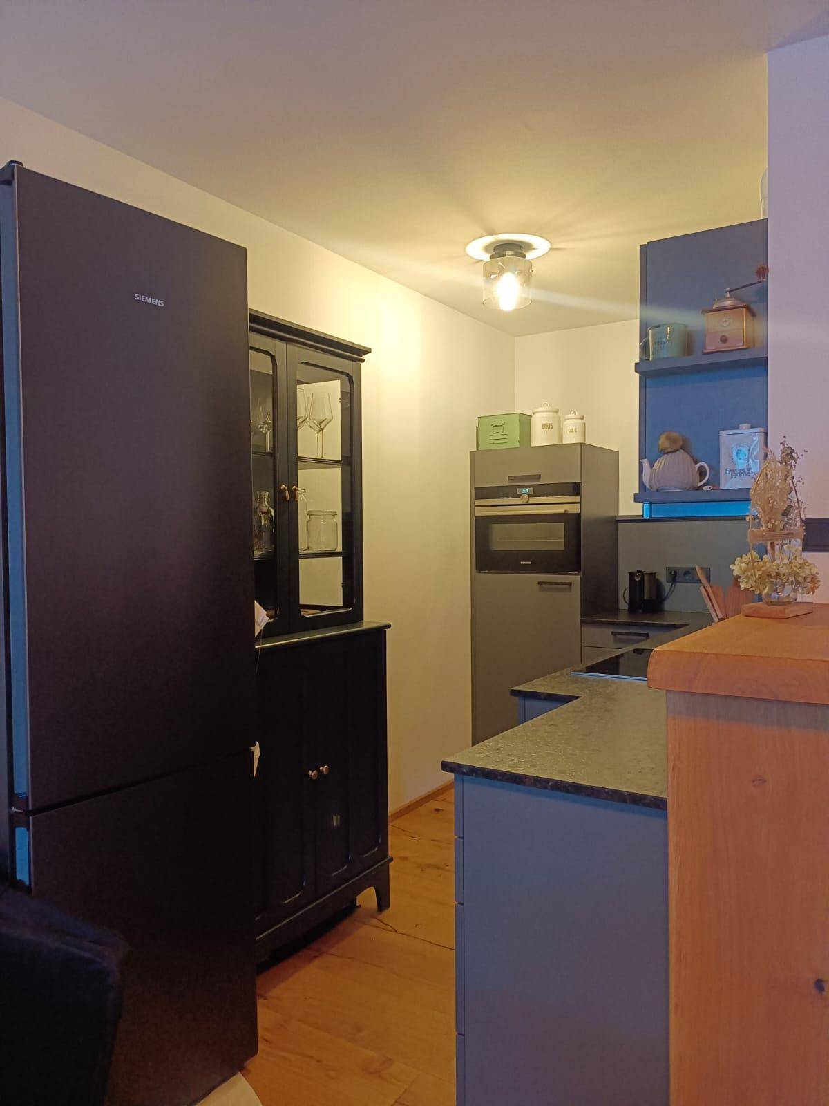 Detailansicht der modernen Küche mit dunklem Kühlschrank und integriertem Backofen.