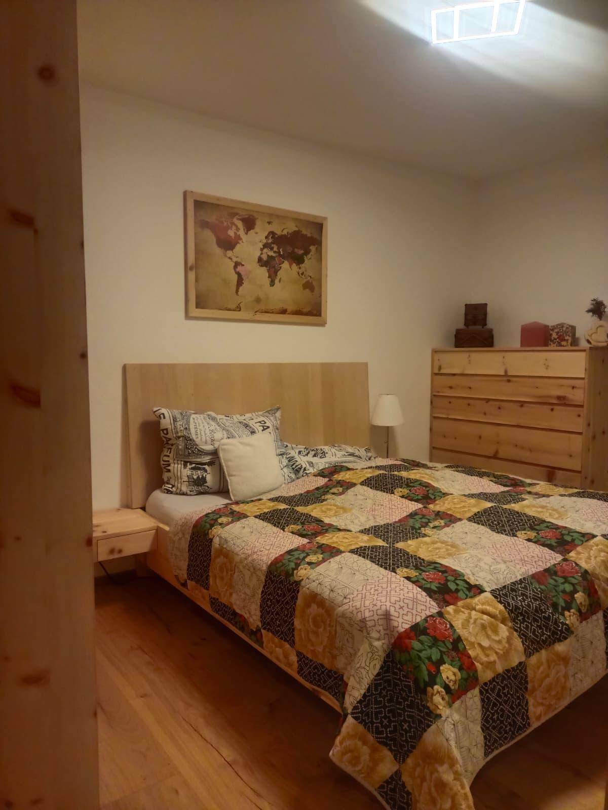 Gemütliches Schlafzimmer mit Holzbett, Nachttischen und einem farbenfrohen Quilt.