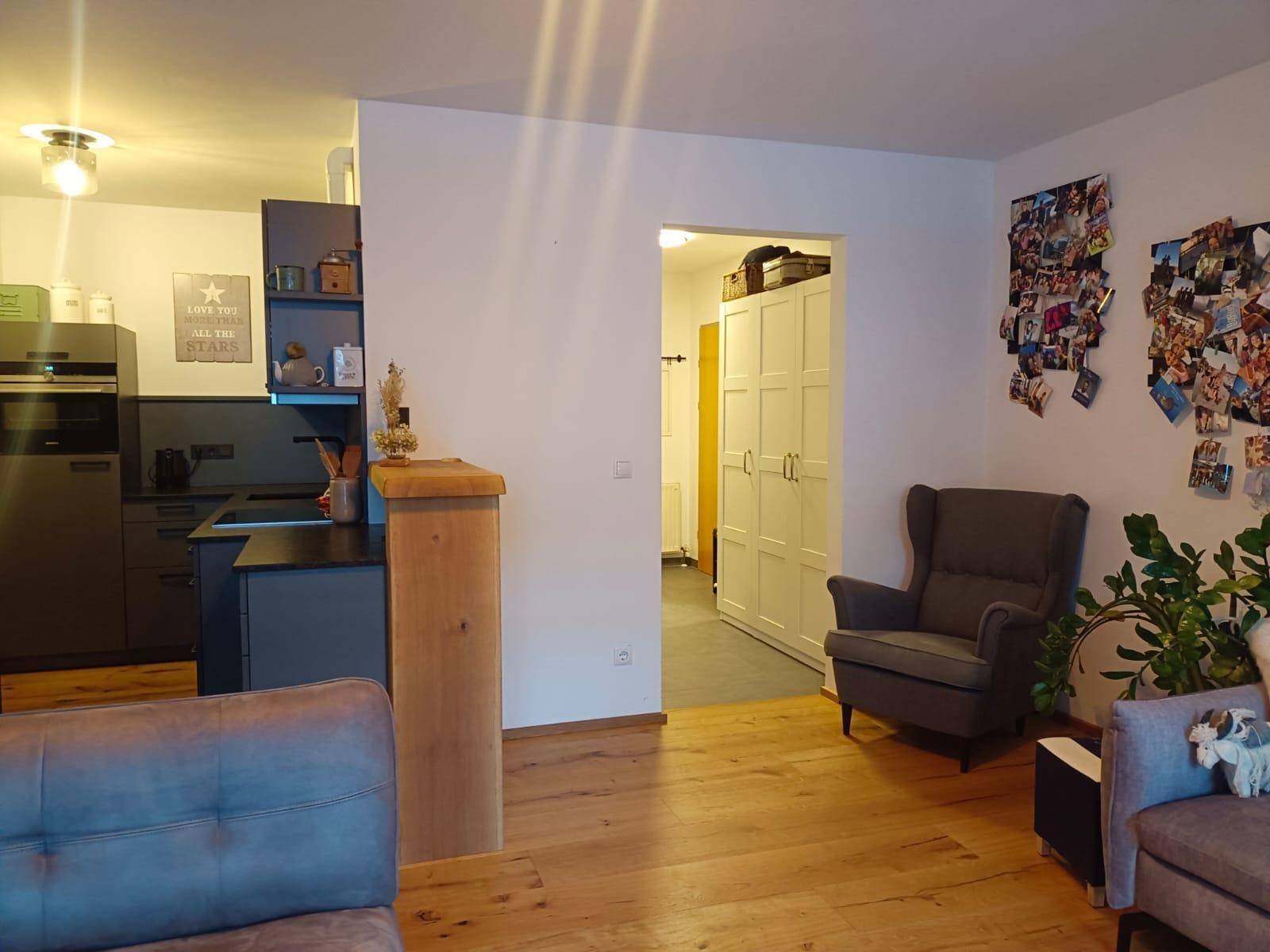 Heller Wohnbereich mit Holzboden, bequemen Sesseln und Übergang zur modernen Küche.