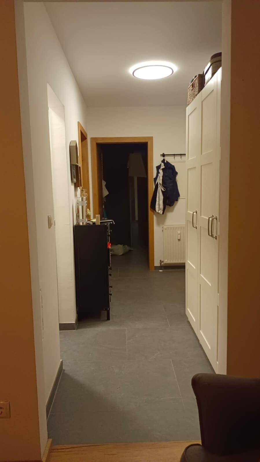 Heller Flur mit modernem Kleiderschrank und Zugang zu weiteren Räumen.