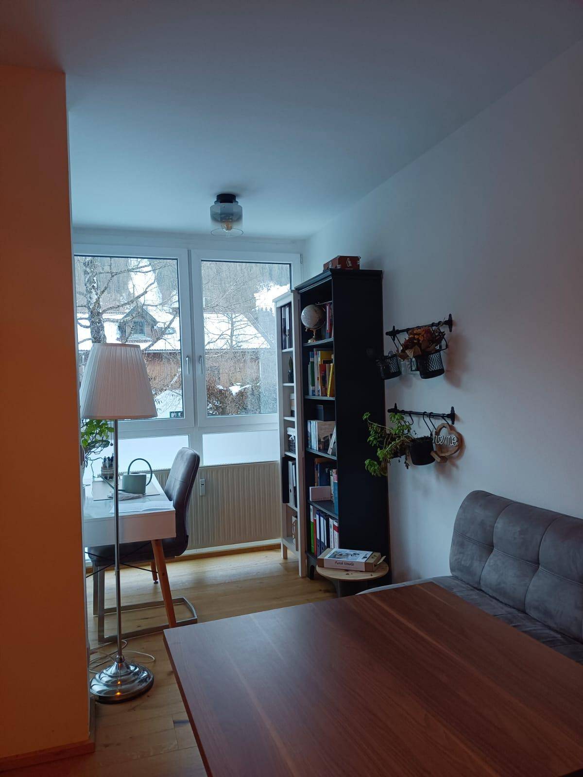 Essbereich mit Holztisch, Sitzbank und einem Arbeitsplatz am Fenster mit Blick ins Grüne.