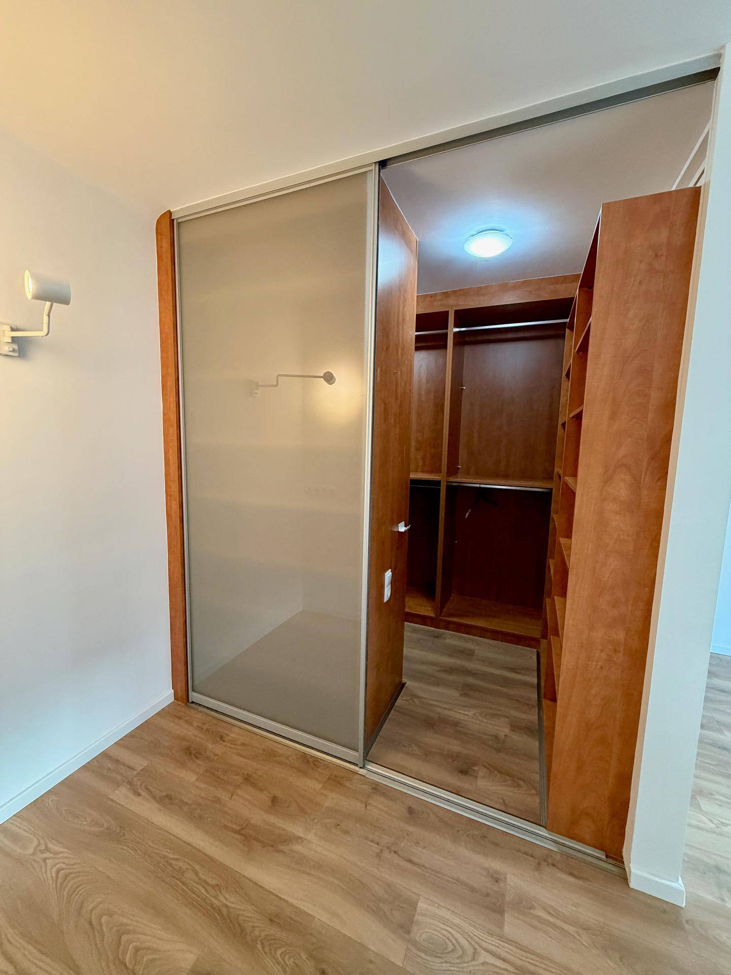 Begehbarer Kleiderschrank mit Schiebetüren und integrierten Regalen.