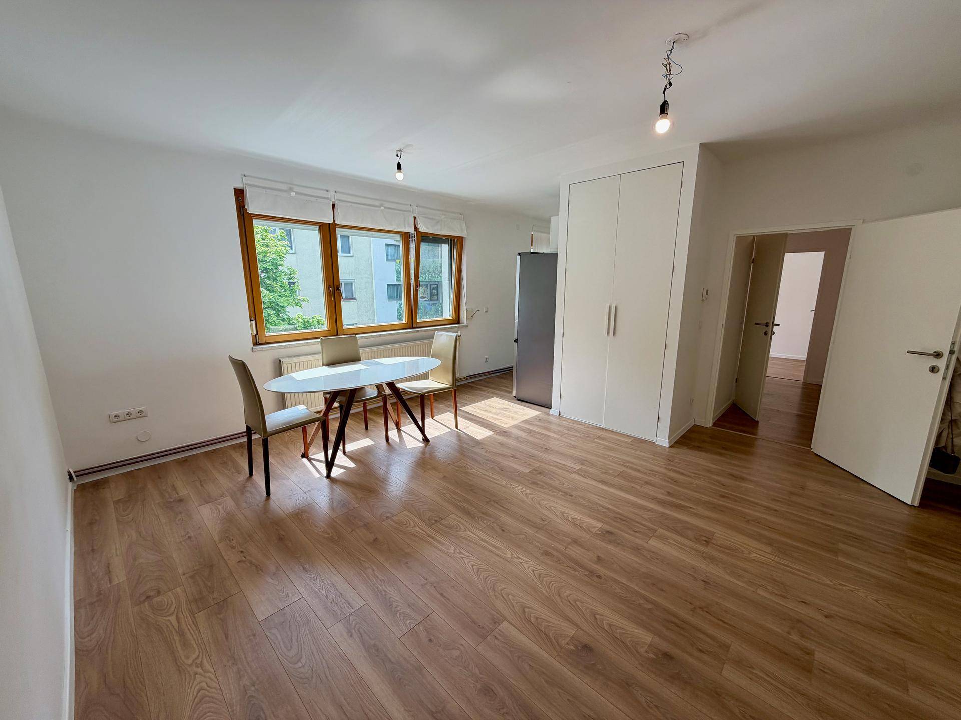 Geräumiges Wohn- und Esszimmer mit Laminatboden und großen Fenstern, bereit zur Einrichtung.