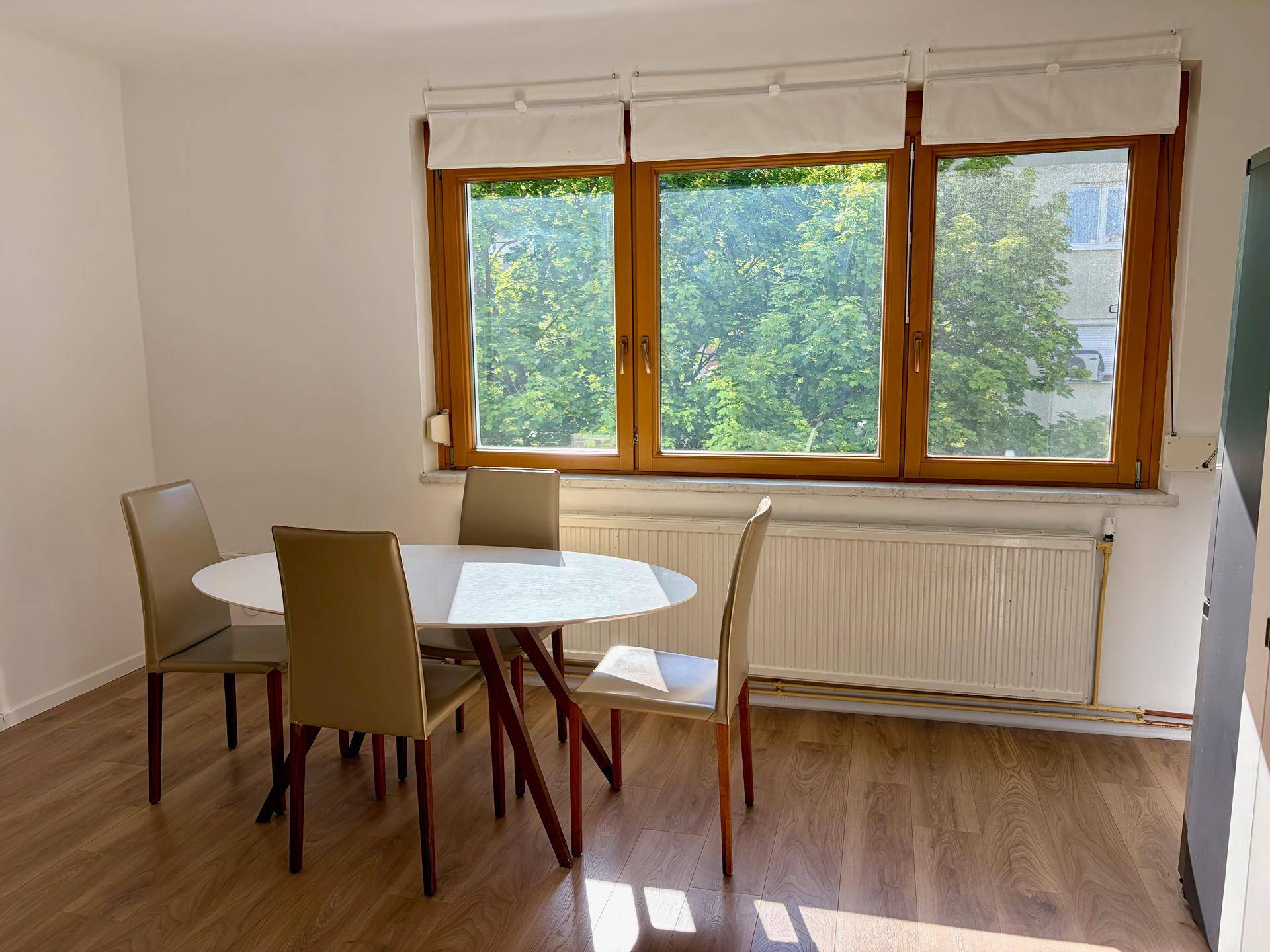 Heller Essbereich mit Laminatboden und großem Fenster mit Blick ins Grüne.