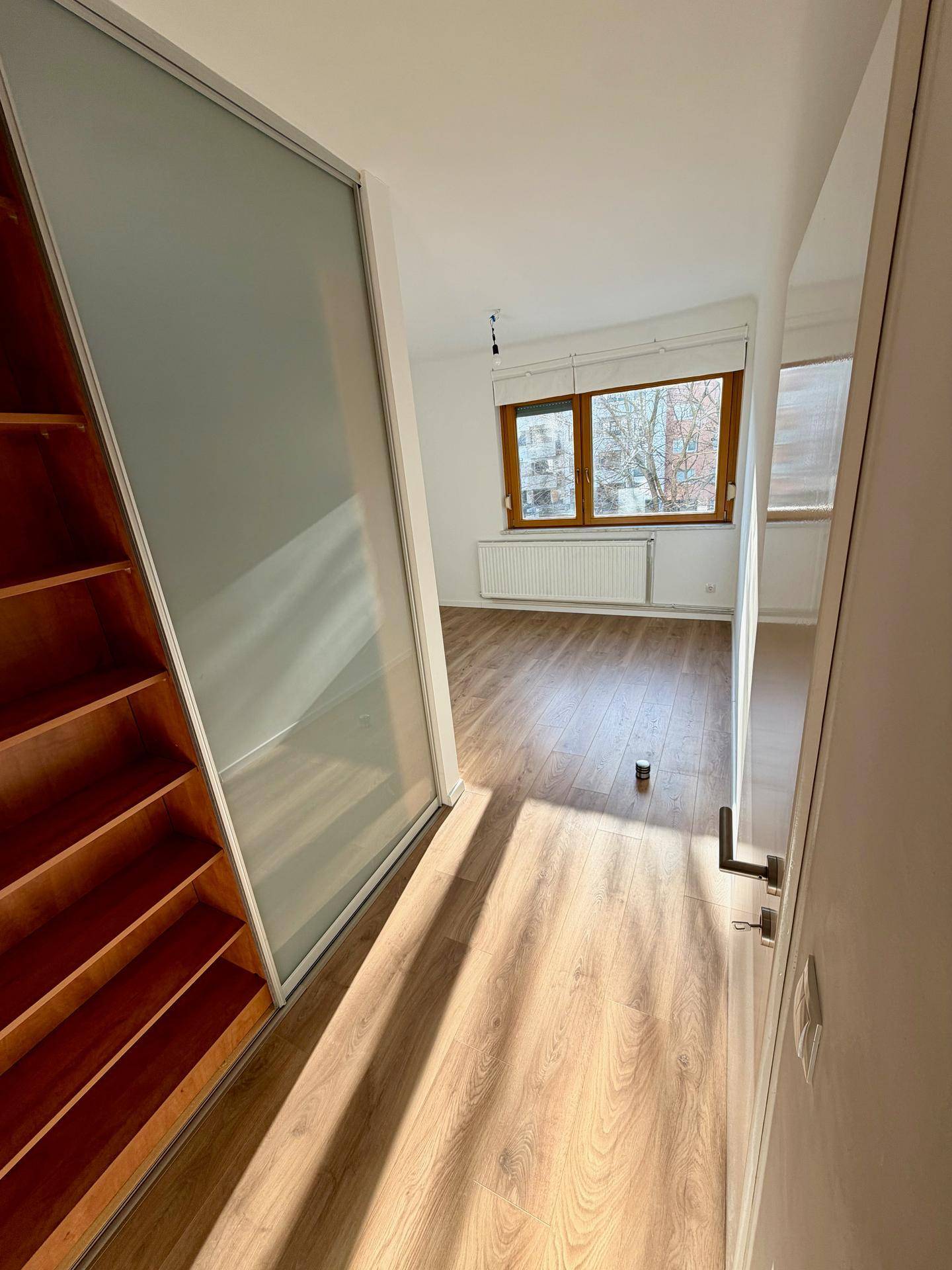 Heller Flur mit Laminatboden und integriertem Schrank, führt zu weiteren Räumen.