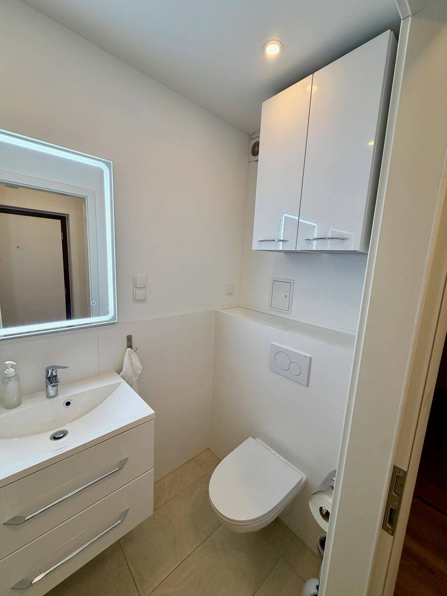 Modernes Badezimmer mit wandhängendem WC, Waschtisch und Spiegelschrank.
