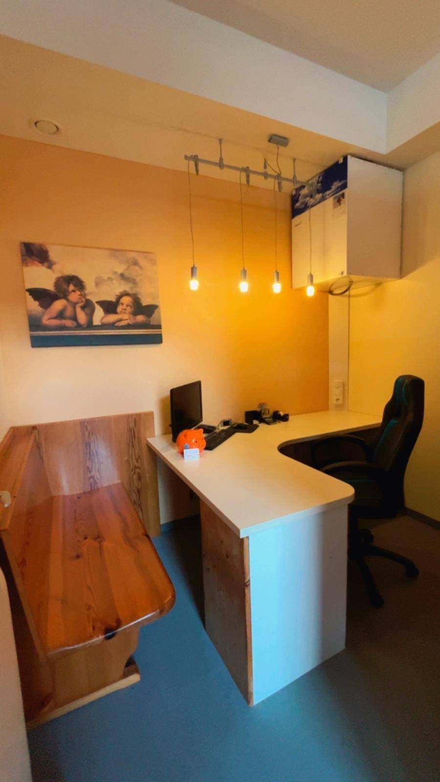 Funktionaler Büroraum mit einem großen Schreibtisch, Bürostuhl und Holzbank.