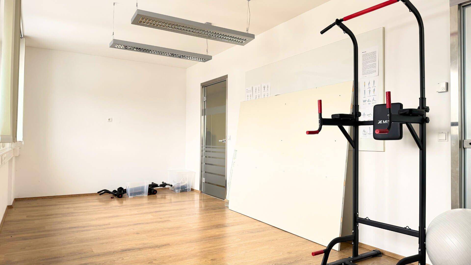 Geräumiger Raum mit Holzboden und Fitnessgeräten, ideal für sportliche Aktivitäten oder als Mehrzweckraum.