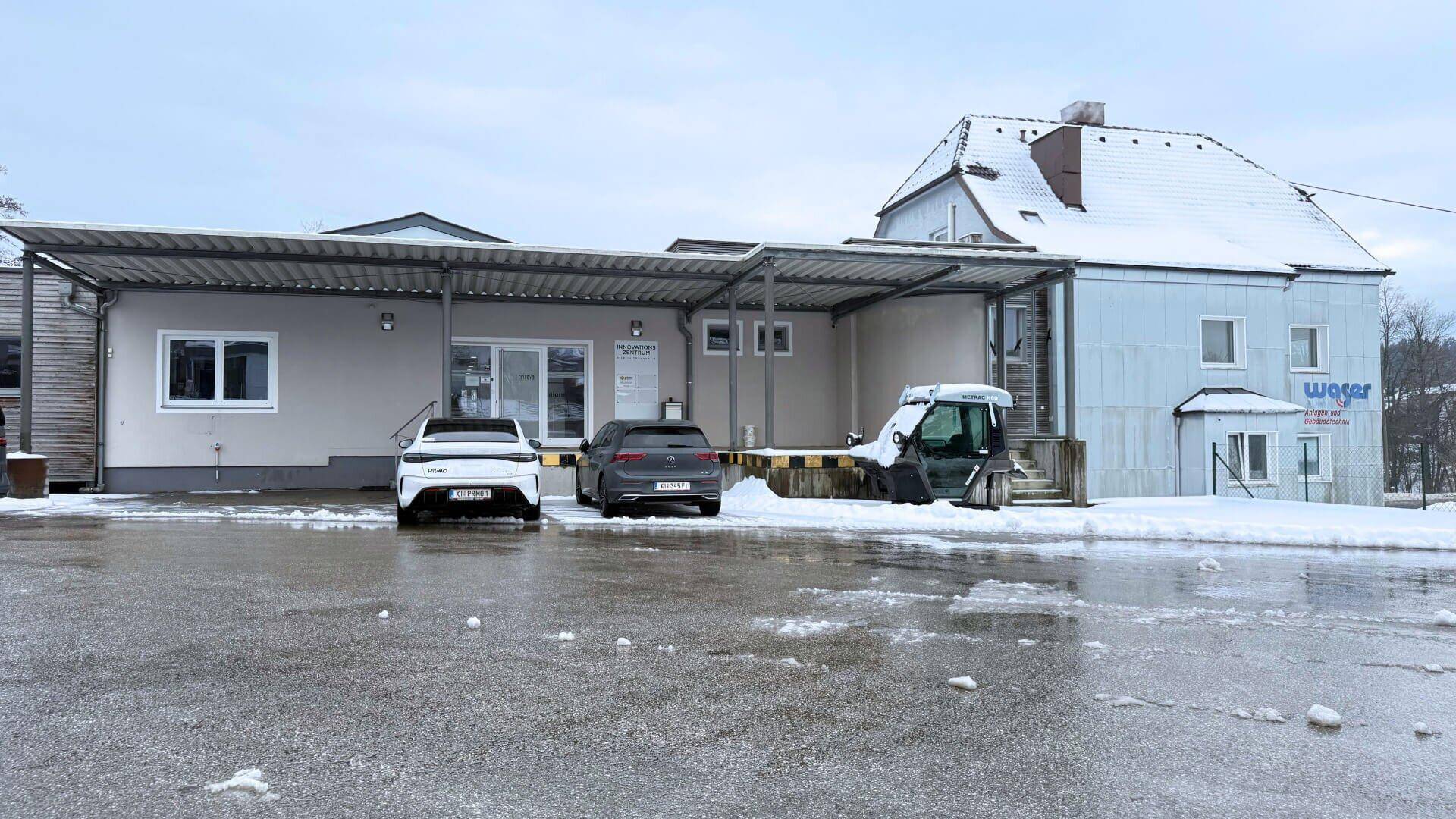 Außenansicht des Gebäudes mit Parkplätzen im Winter, zeigt die moderne Architektur und Umgebung.