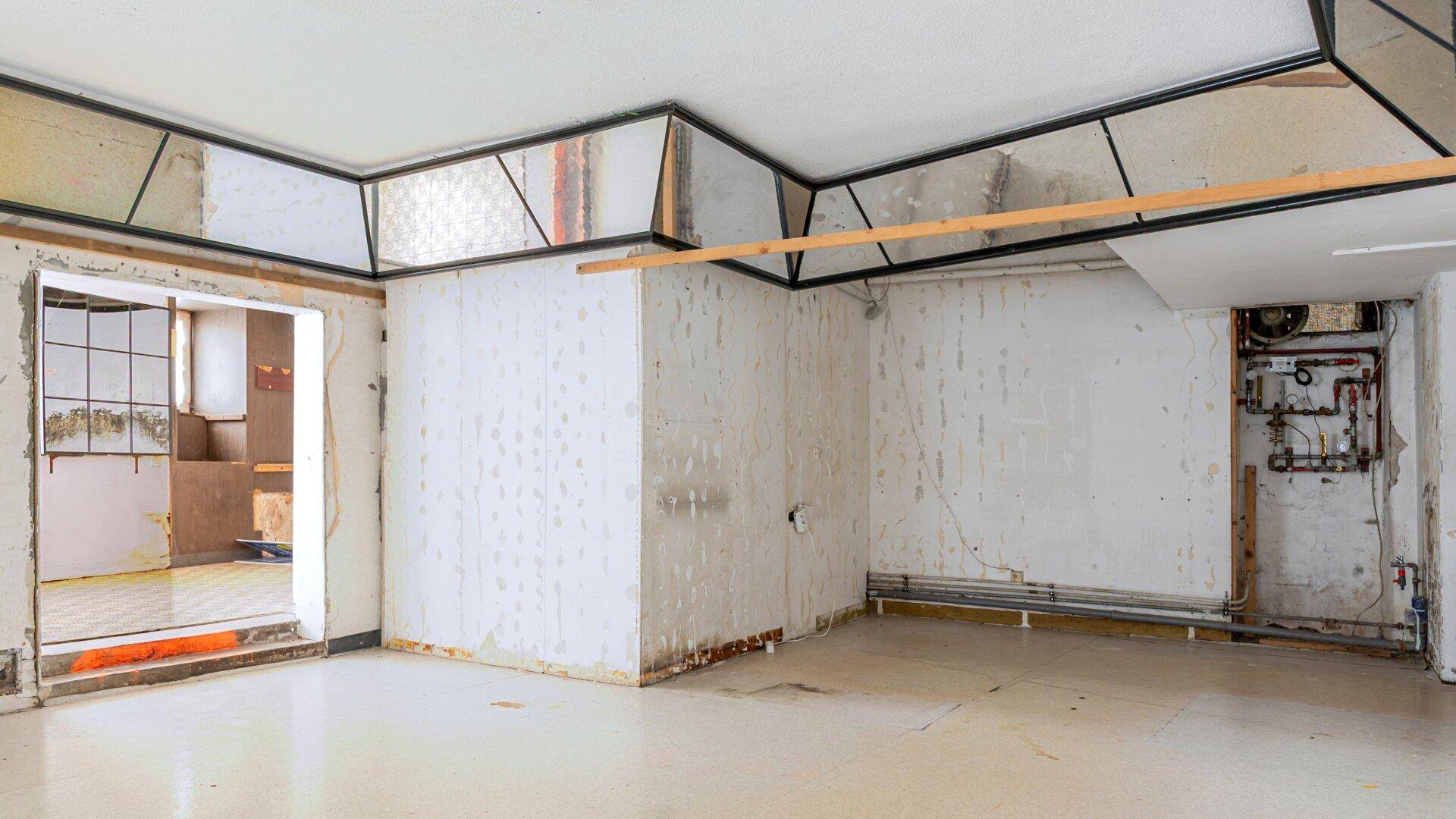 Unfertiger Raum mit sichtbaren Installationen und Renovierungsbedarf.