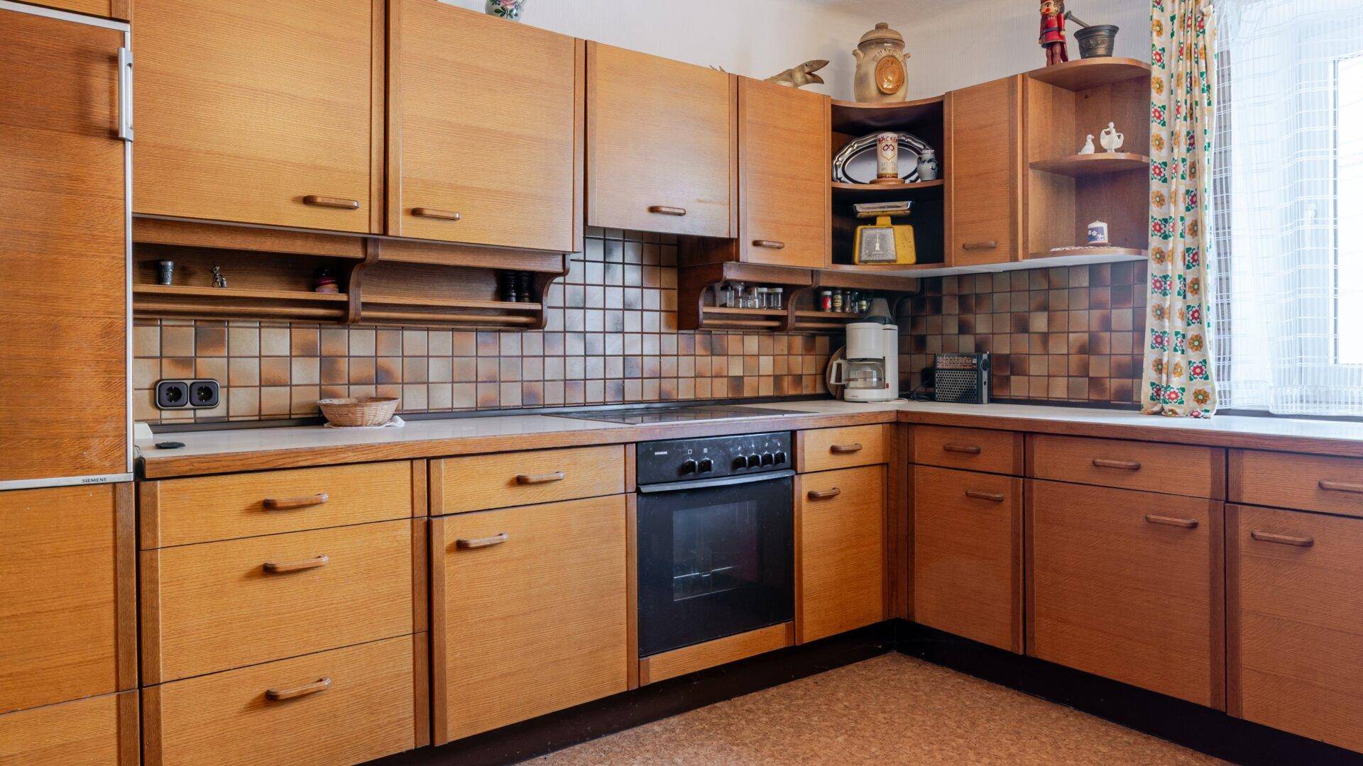 Traditionelle Holzküche mit braunen Fliesen, integriertem Backofen und viel Stauraum.