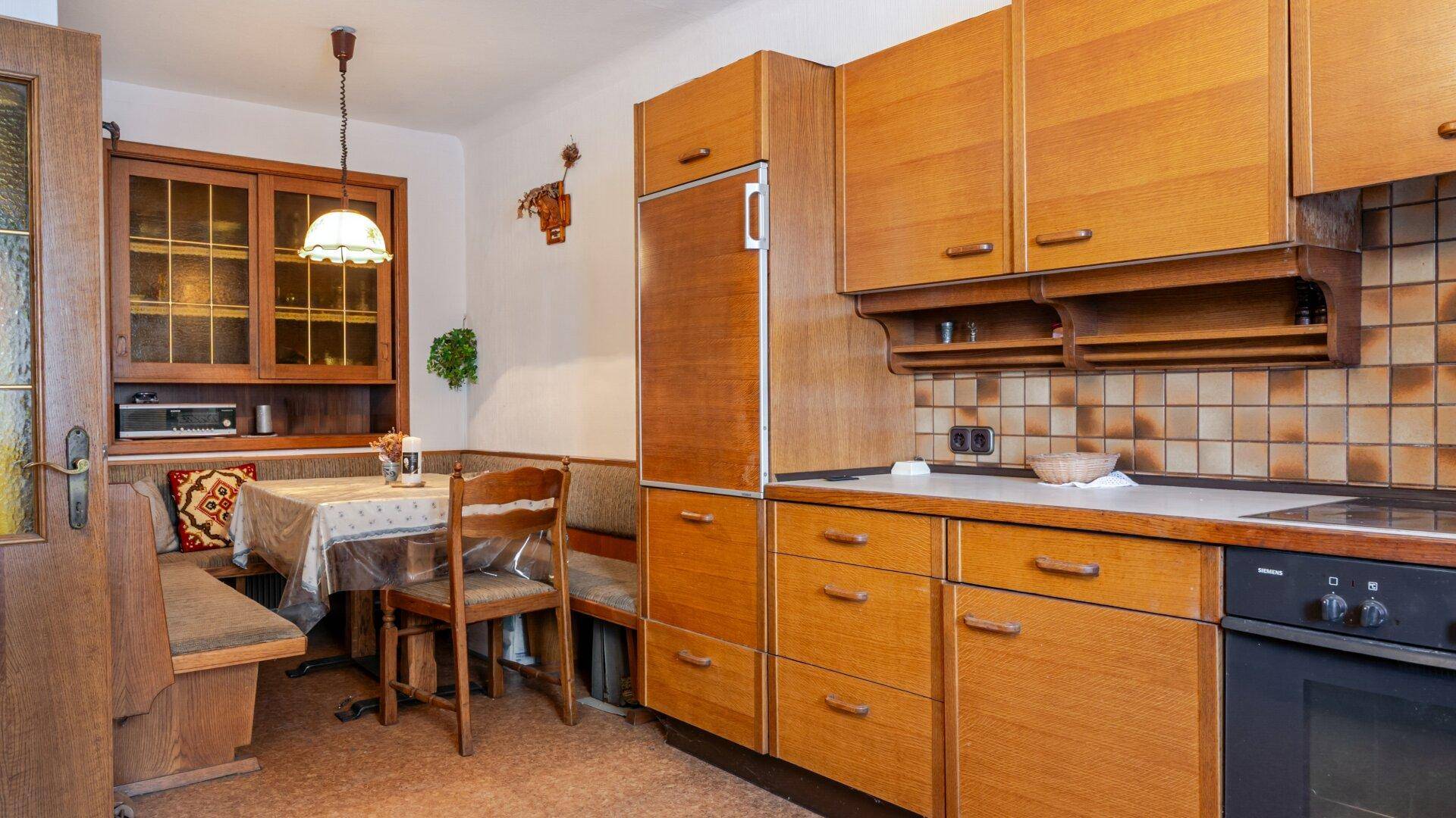 Rustikale Küche mit Holzeinbauten, integriertem Kühlschrank und gemütlicher Essecke.