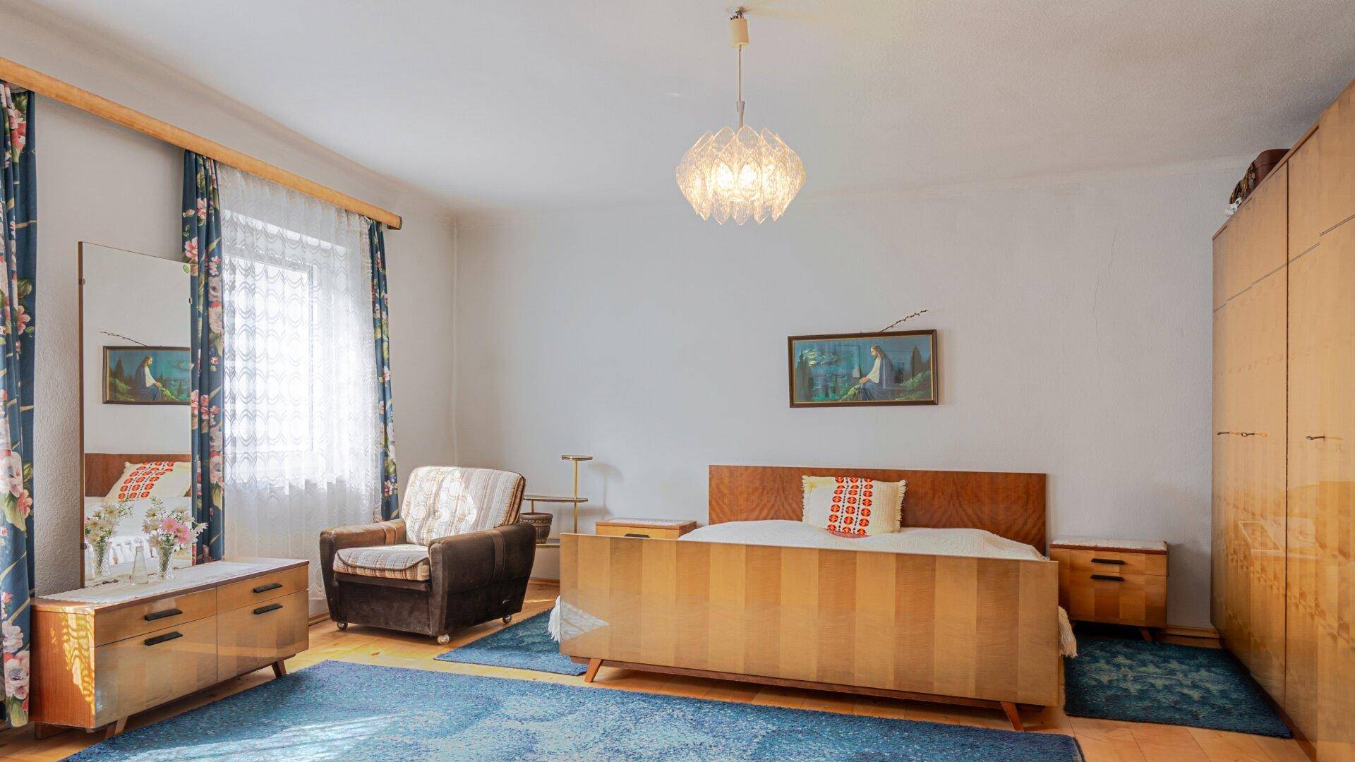 Schlafzimmer mit Vintage-Möbeln, Holzboden und großem Kleiderschrank.