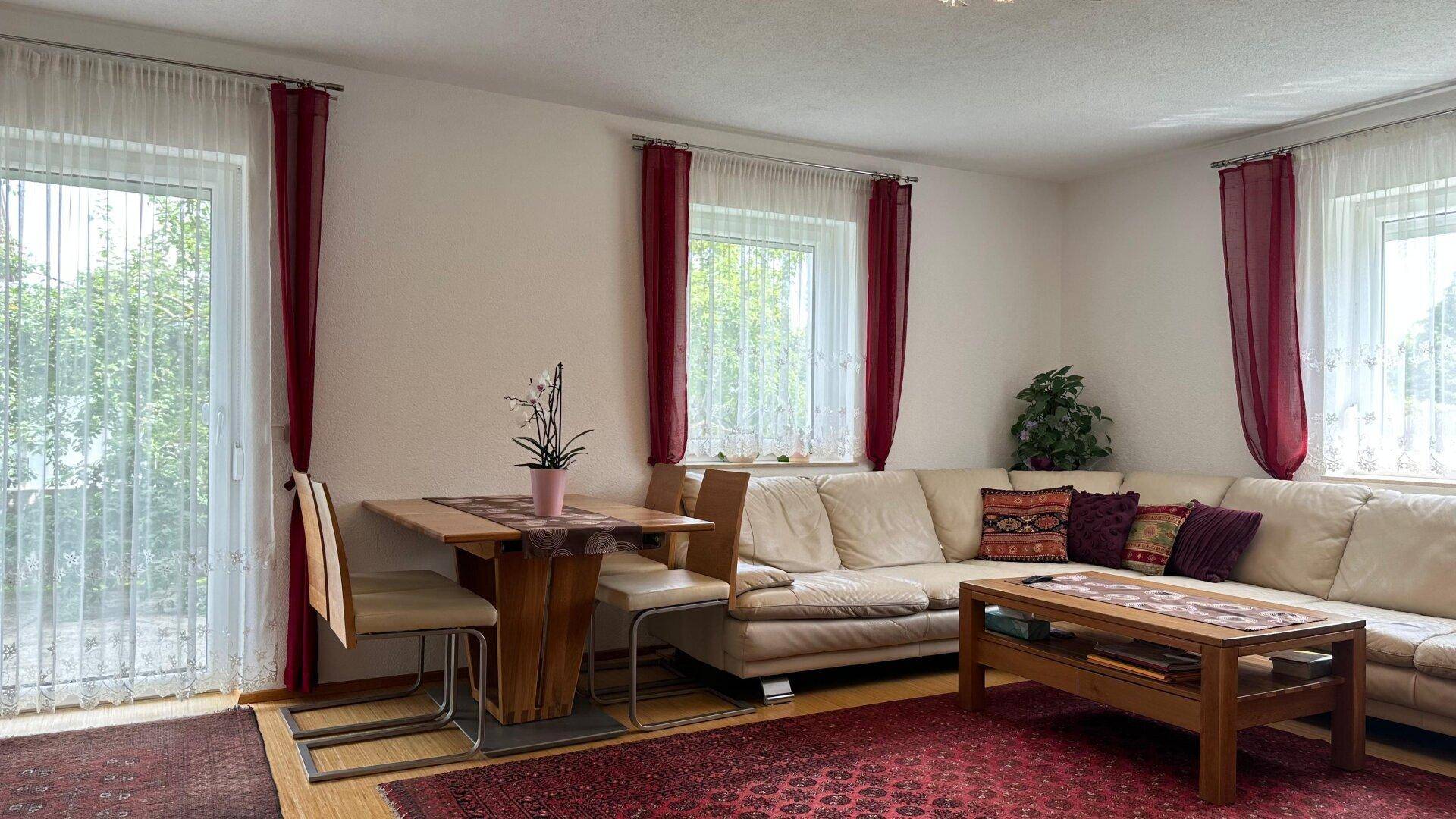 Heller Wohn- und Essbereich mit Zugang zum Balkon, ausgestattet mit bequemer Couch und Esstisch.