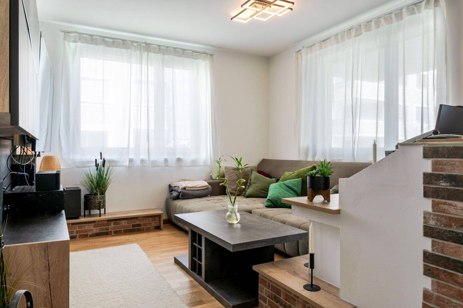 Helles Wohnzimmer mit beigem Ecksofa, Holzboden und modernem Couchtisch, ideal zum Entspannen.
