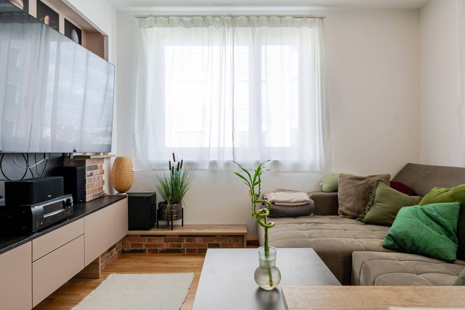 Modernes Wohnzimmer mit großem Flachbildfernseher, Medienschrank und bequemer Sitzecke.