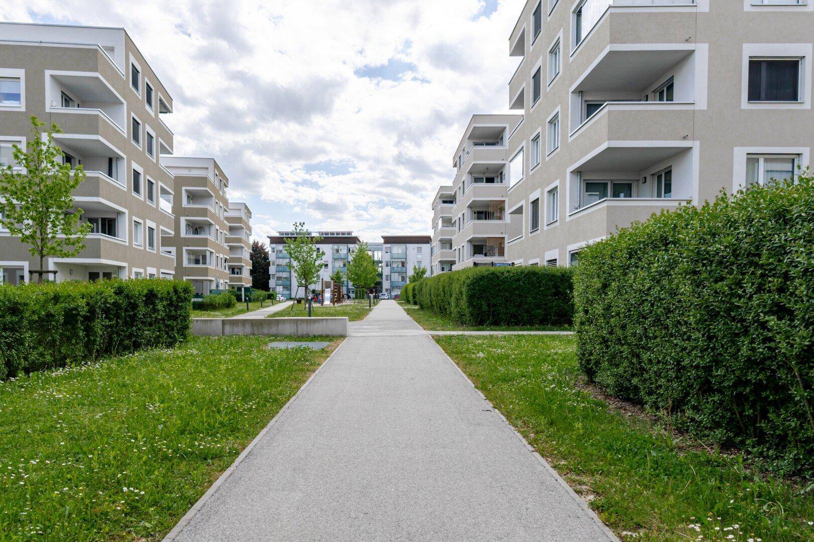 Moderne Wohnanlage mit gepflegten Grünflächen und Gehwegen zwischen den Gebäuden.
