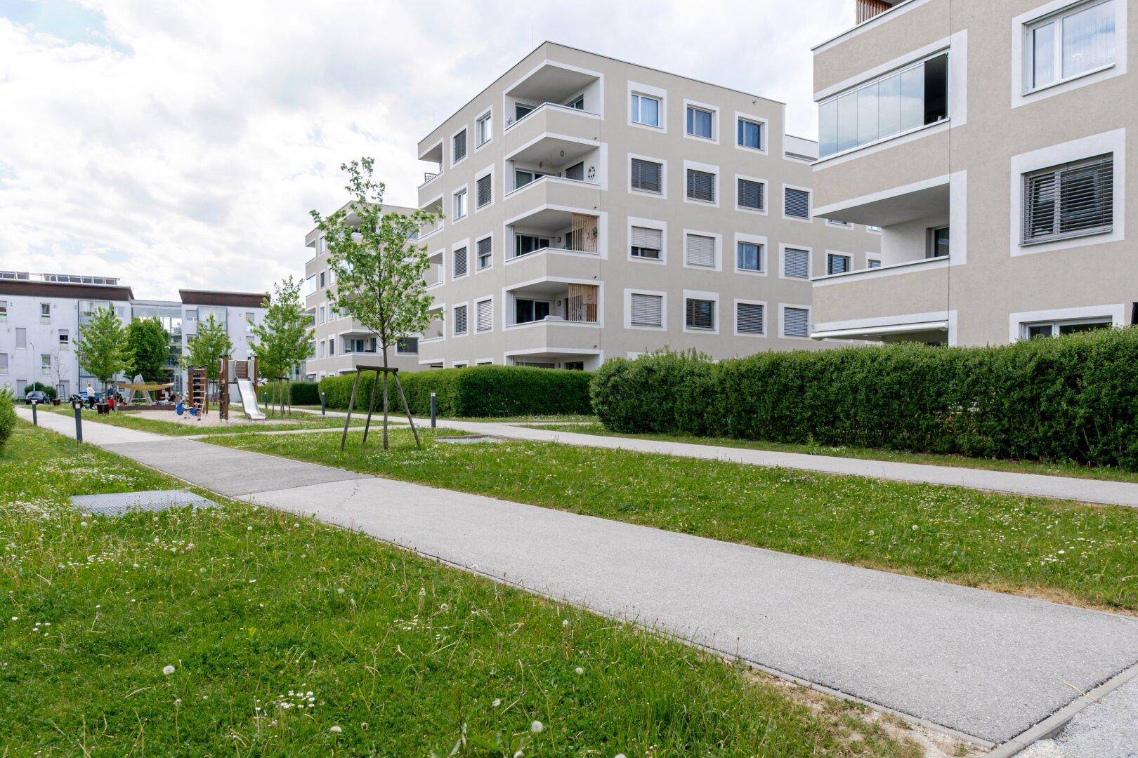 Attraktive Wohnanlage mit modernen Gebäuden, weitläufigen Grünflächen und einem Spielplatz.