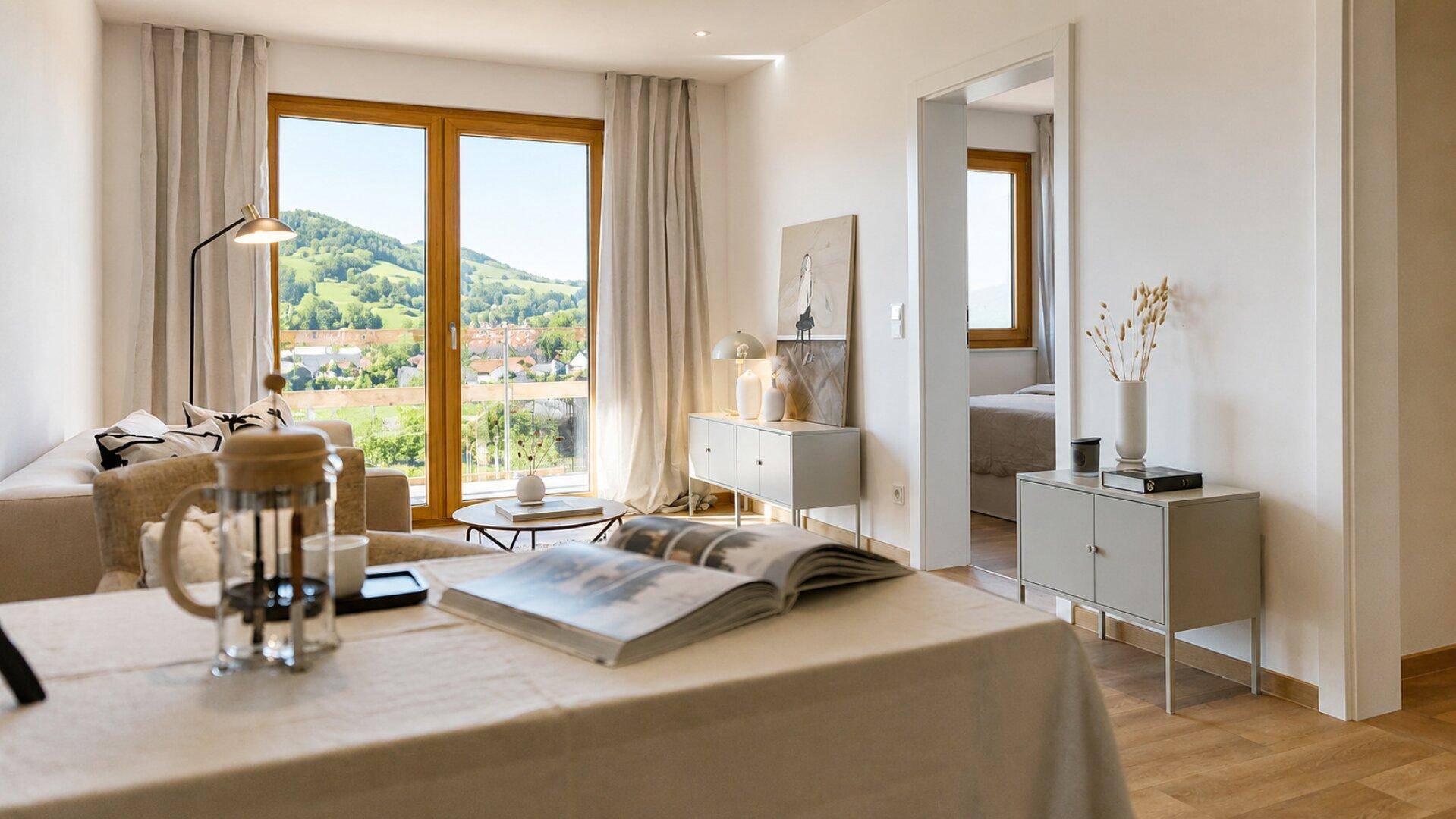 Lichtdurchflutetes Wohnzimmer mit großen Fenstern und weitem Blick auf die grüne Hügellandschaft.