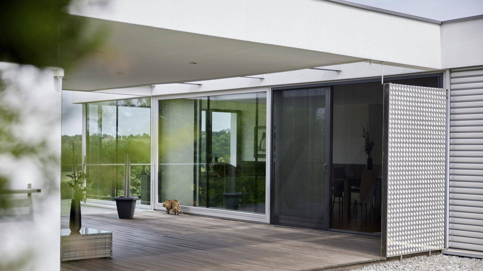 Überdachte Terrasse mit Holzdeck, großen Schiebetüren und einem dekorativen Sichtschutz.