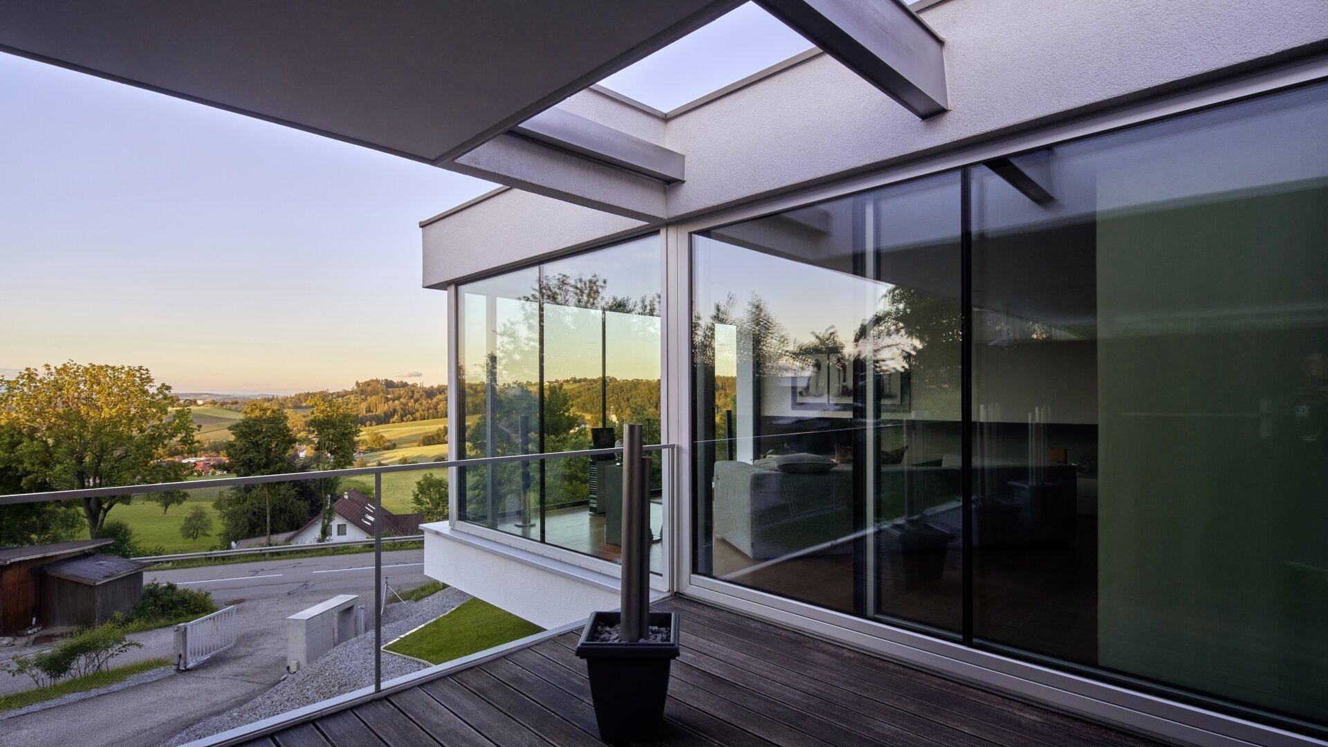 Geräumiger Balkon mit Glasgeländer und weitem Panoramablick über die umliegende Landschaft.