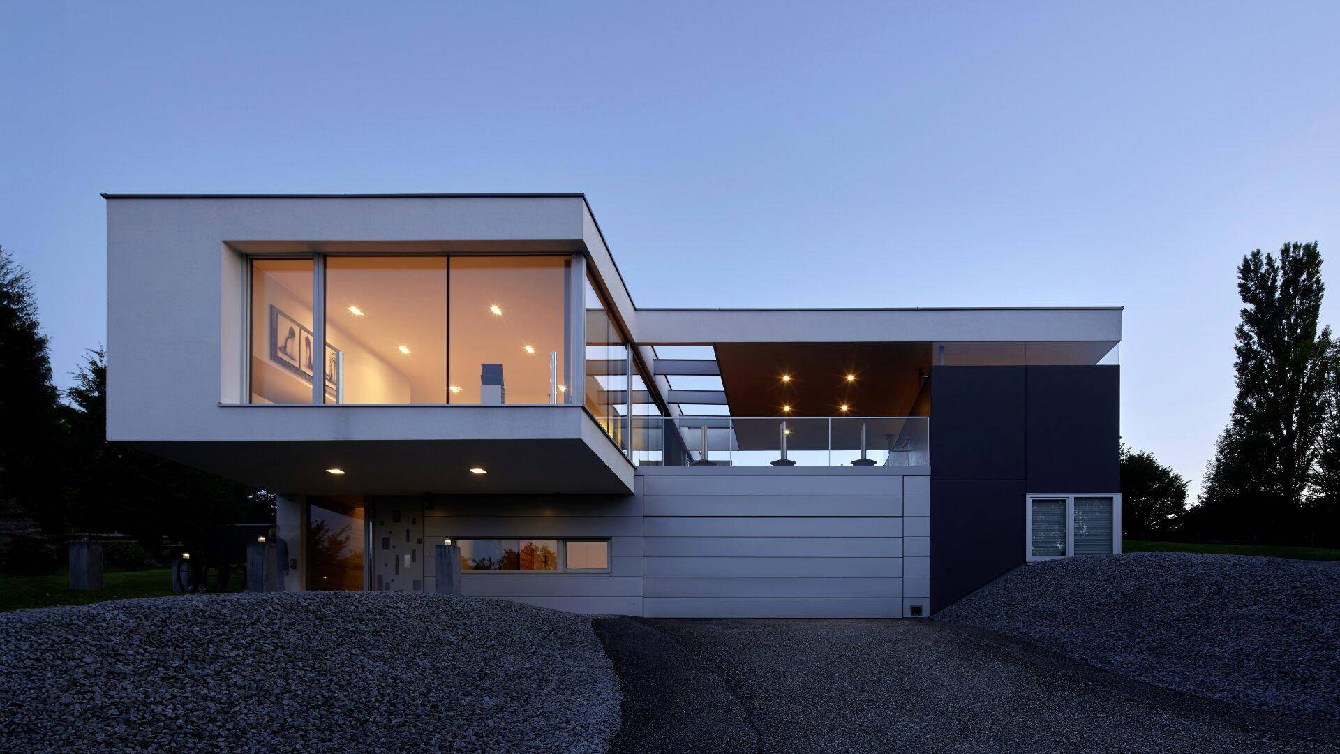 Exklusive moderne Villa mit weitläufigen Glasflächen und eleganter Beleuchtung bei Nacht.