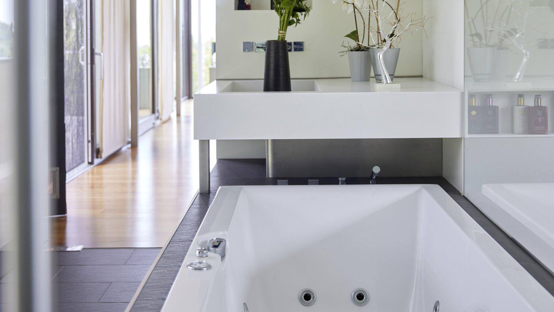 Moderne Badewanne mit Whirlpool-Funktion und stilvollem Doppelwaschbecken in hellem Design.
