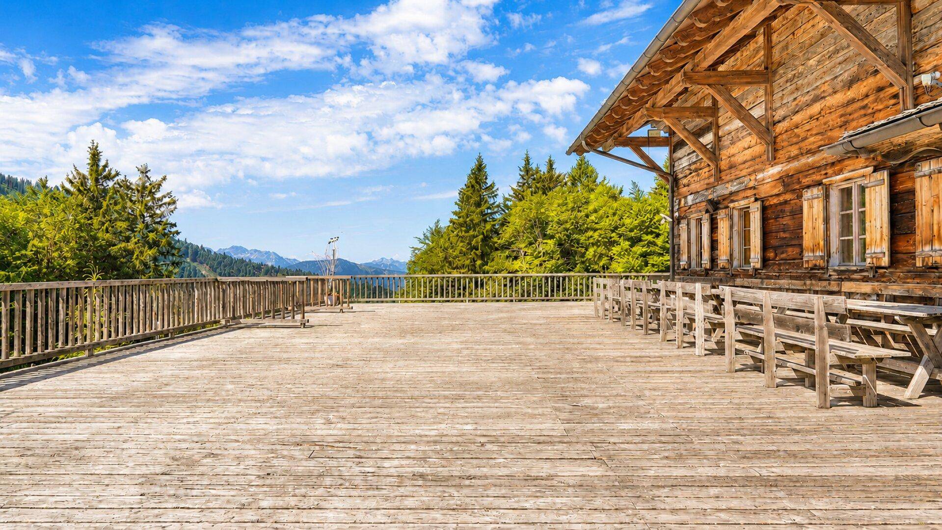 Weitläufige Holzterrasse mit rustikalen Sitzgelegenheiten und Panoramablick auf die umliegende Berglandschaft.