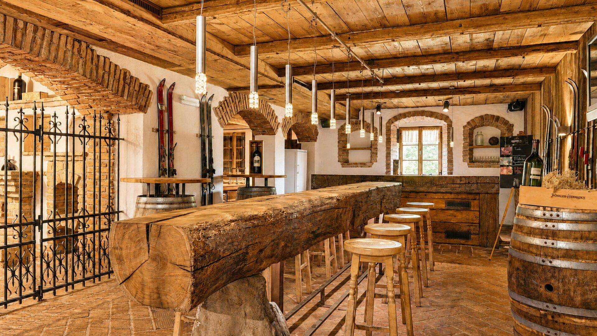 Rustikale Bar mit einem massiven Holzstamm als Theke, Ziegelgewölben und traditioneller Skidekoration.