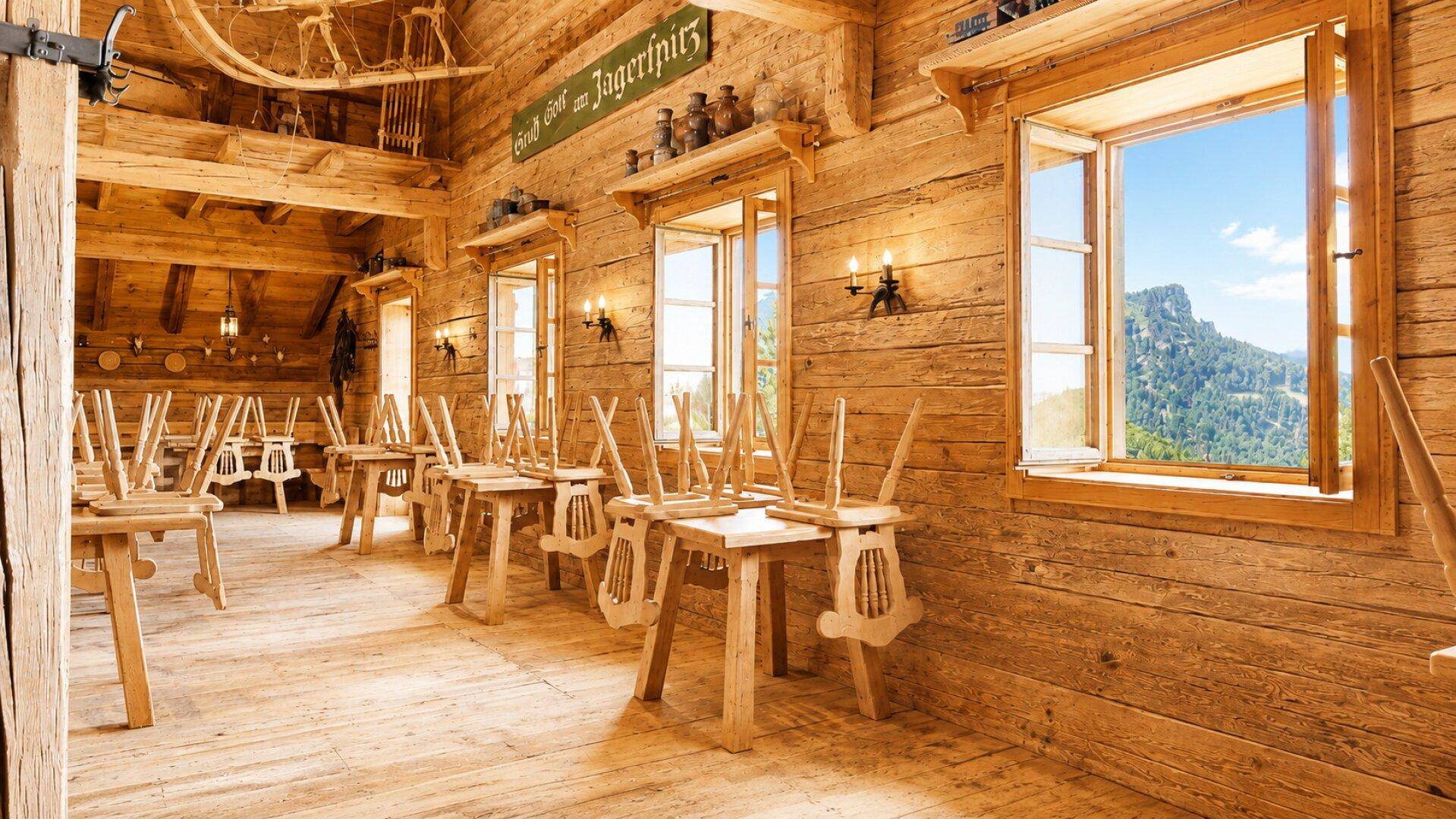 Großer Speisesaal mit zahlreichen Holztischen und Stühlen, Holzböden und Fenstern mit Bergblick.