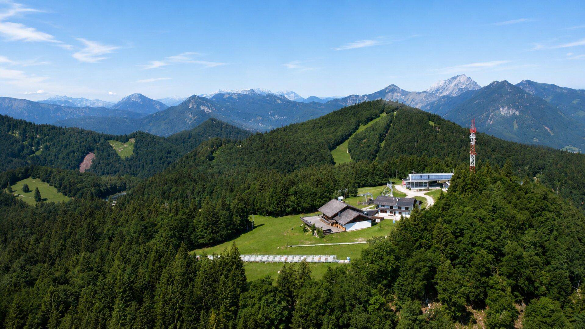 Sehr weite Luftaufnahme der Berglandschaft mit dem Gebäudekomplex inmitten von Wäldern und Bergen.