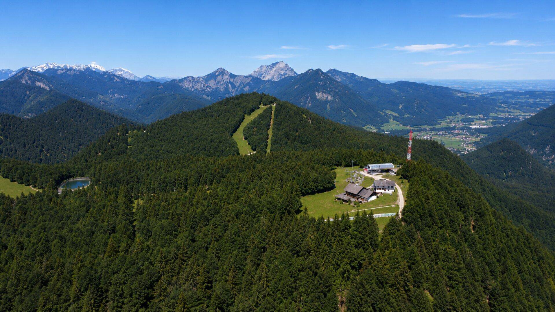 Extrem weite Luftaufnahme der gesamten Bergkette mit dem Gebäudekomplex und einem kleinen Bergsee.