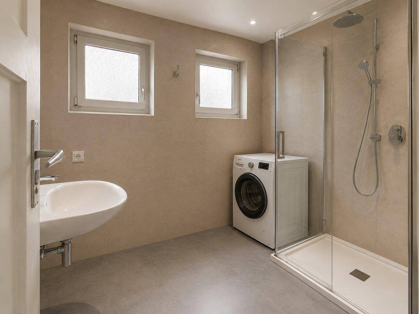 Modernes Badezimmer mit Dusche, Waschbecken, Waschmaschine und zwei Fenstern für Tageslicht.