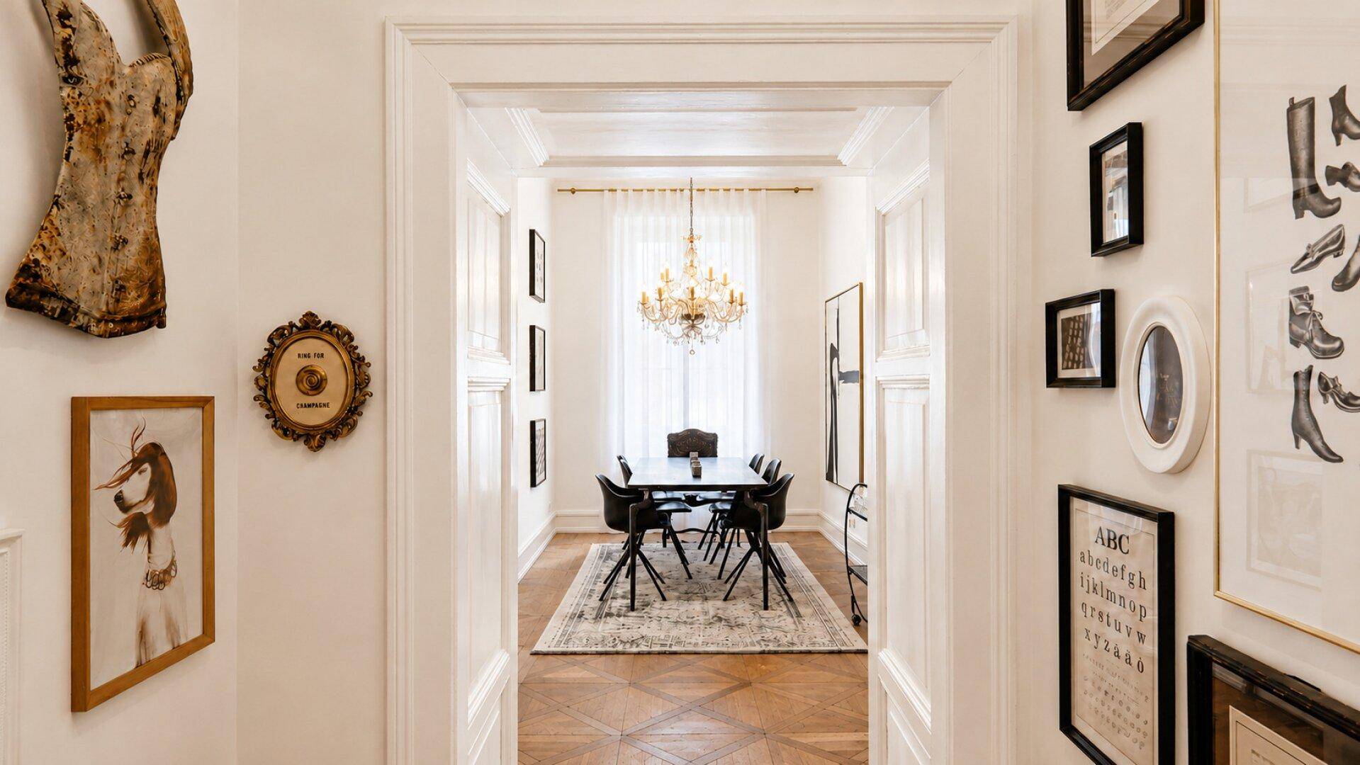 Elegantes Esszimmer mit dunklem Esstisch, modernen Stühlen und Kronleuchter, verbunden durch eine breite Türöffnung.