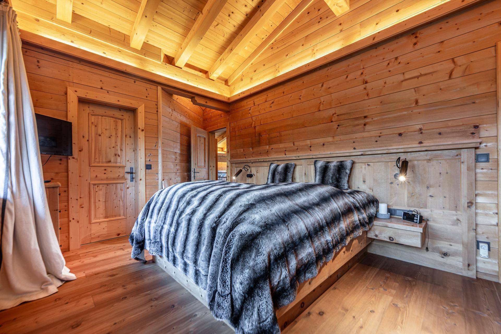 Schlafzimmer mit Holzwänden, Holzboden und Einbauschränken im traditionellen Chalet-Stil.