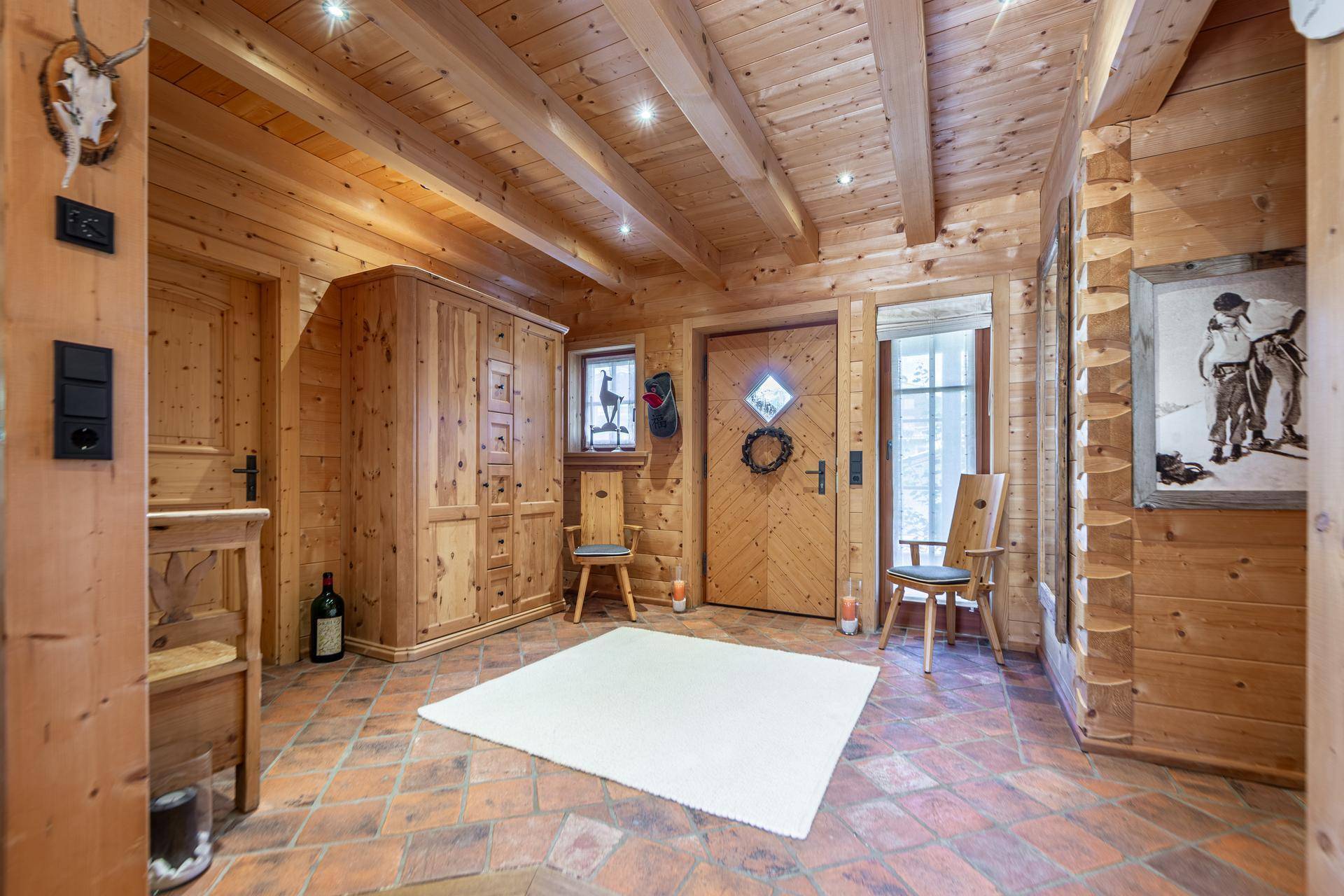 Eingangsbereich im Chalet-Stil mit Terrakotta-Fliesen, Holzvertäfelung und traditionellen Möbeln.