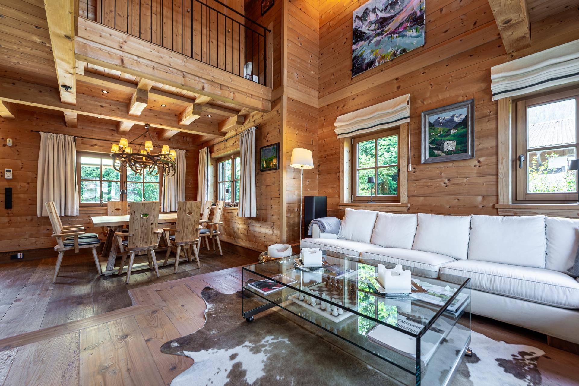 Gemütlicher Wohn-Essbereich mit großer Couch, Holzbalkendecke und Blick auf die Galerie.