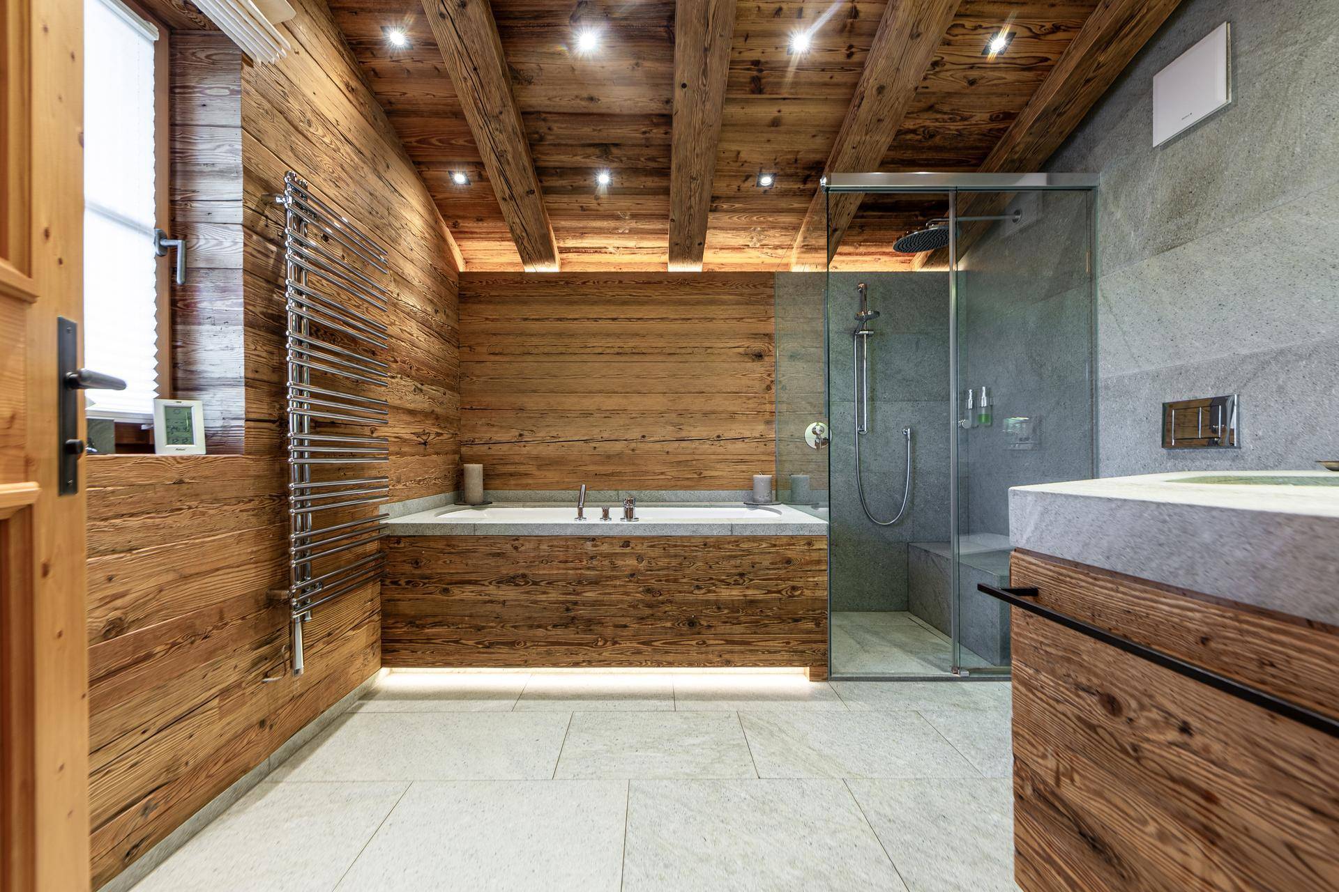 Modernes Badezimmer mit Holzvertäfelung, Badewanne, begehbarer Dusche und Steinfliesen.
