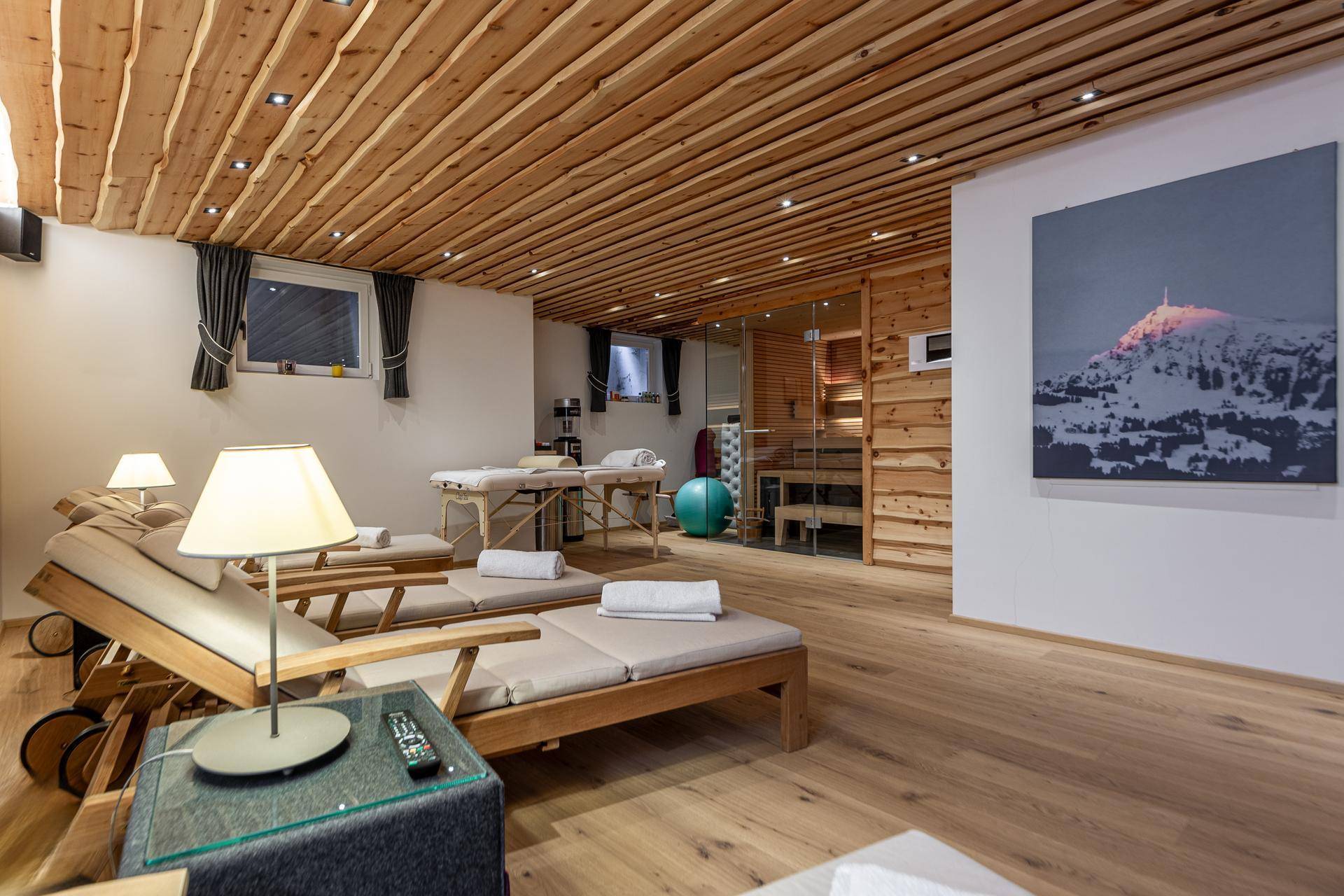 Moderner Wellnessbereich mit Liegestühlen, Massageliegen und einer sichtbaren Sauna.
