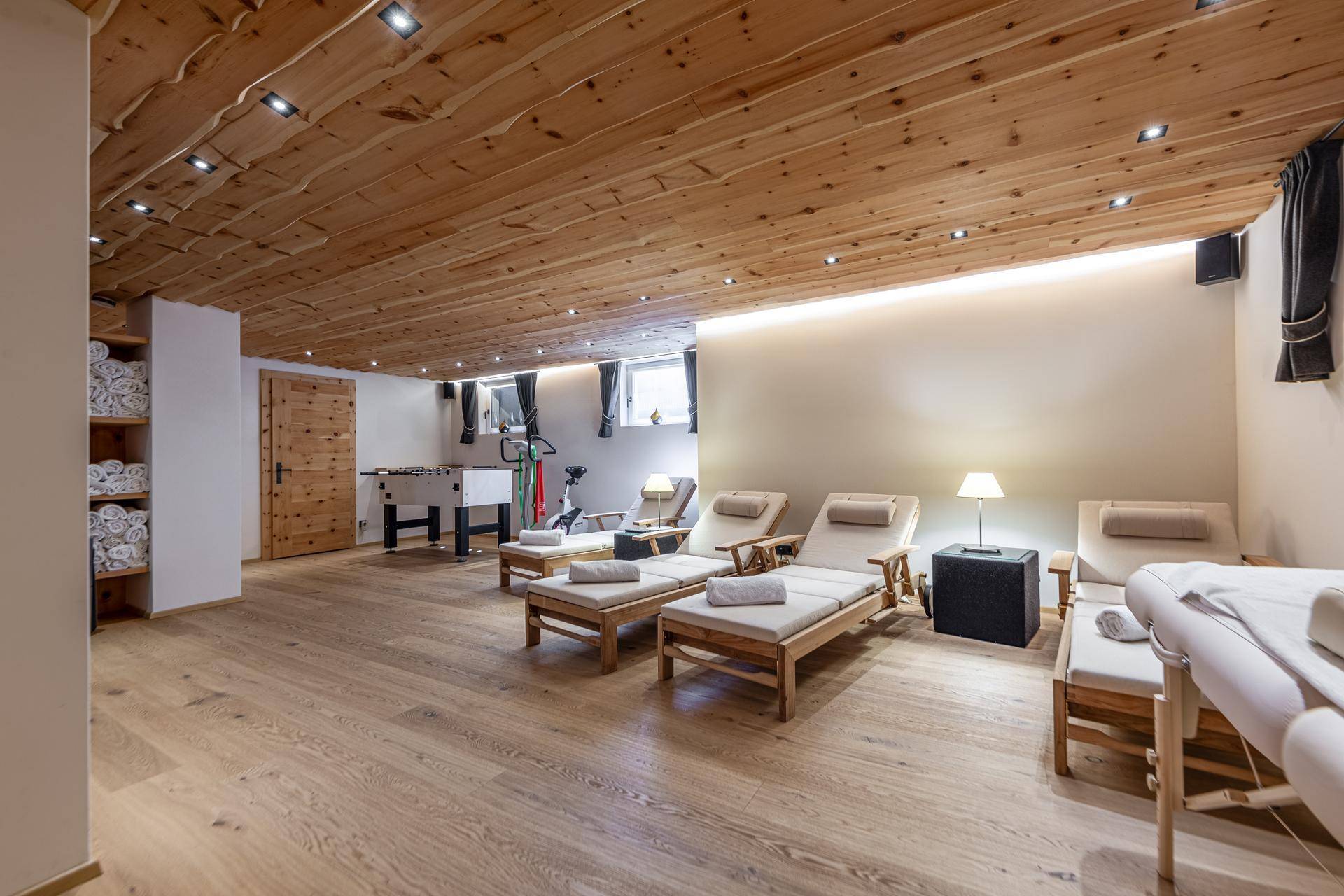 Großer Wellnessbereich mit Liegestühlen, Massageliegen und einem Tischfußballspiel.