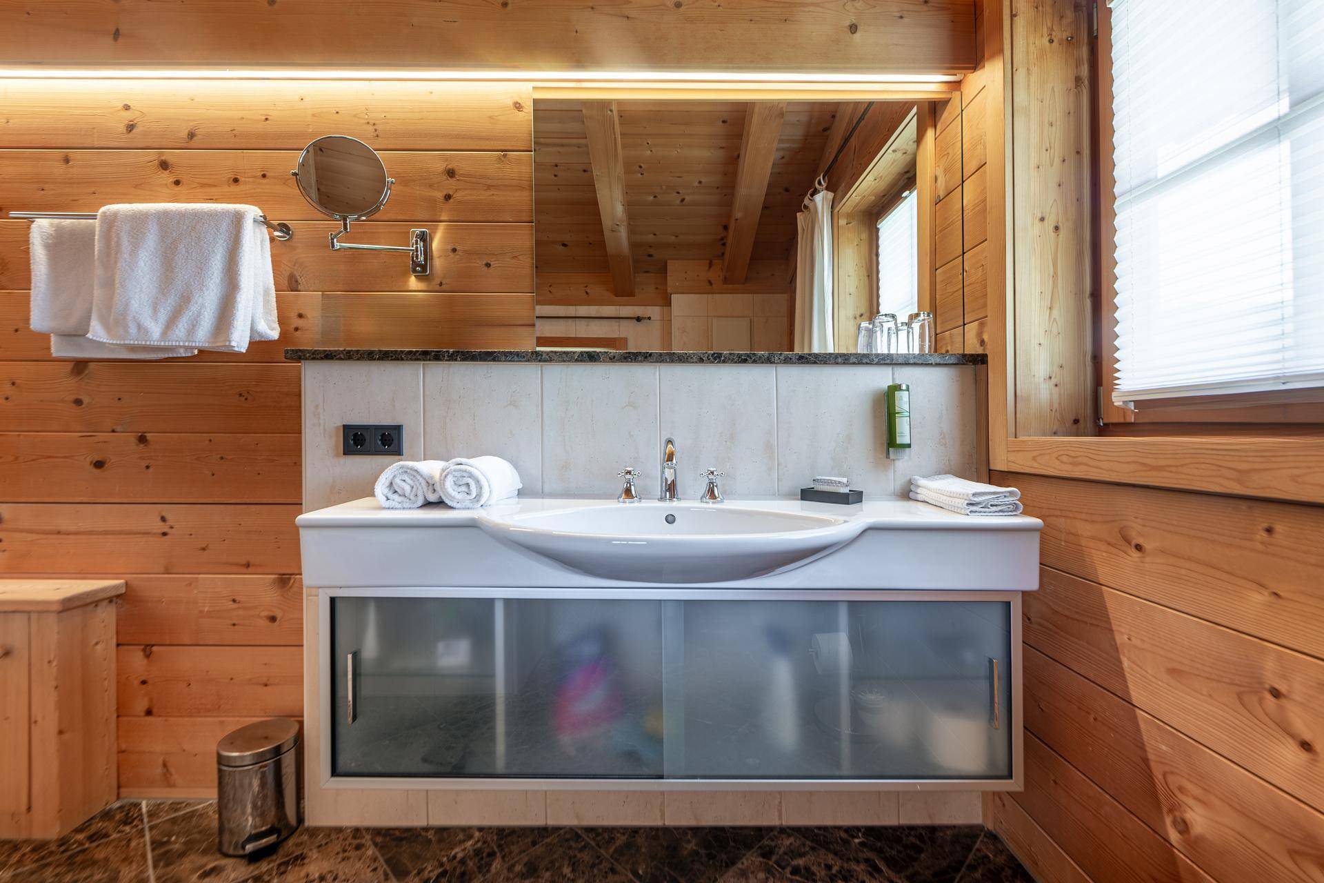 Modernes Badezimmer mit Einzelwaschbecken, großem Spiegel und Holzvertäfelung.