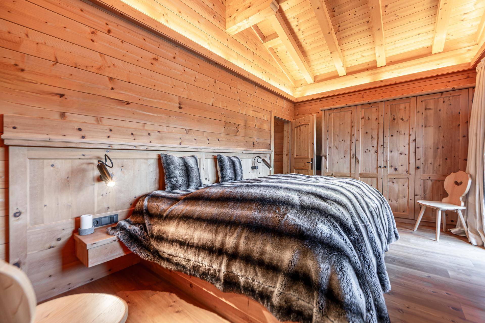 Schlafzimmer mit Holzwänden, Holzboden und Einbauschränken im traditionellen Chalet-Stil.