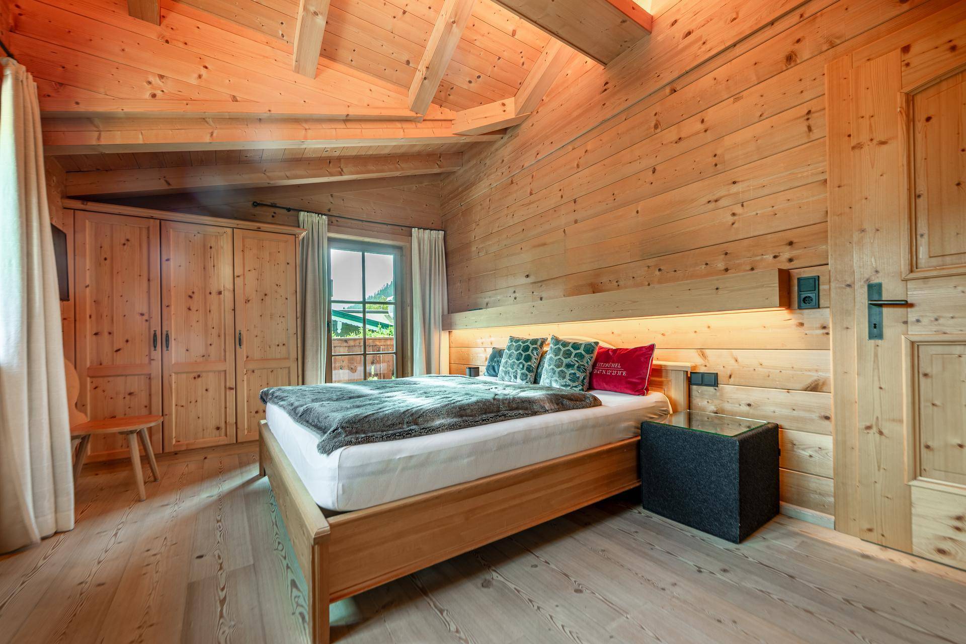 Gemütliches Schlafzimmer mit Holzwänden, Holzboden und einem großen Doppelbett.