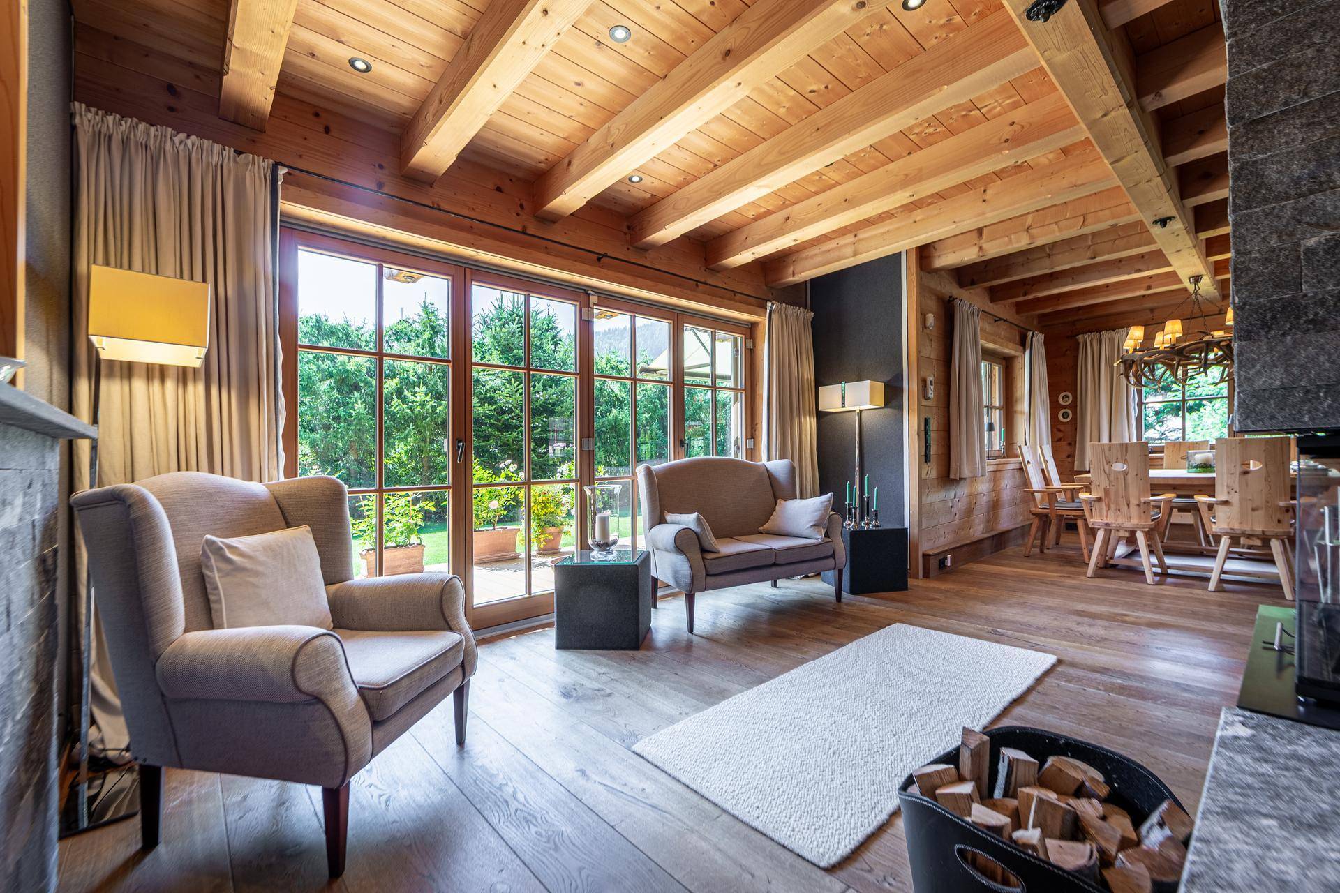Gemütlicher Wohn- und Essbereich mit Holzbalkendecke, großen Fenstern und Zugang zur Terrasse.